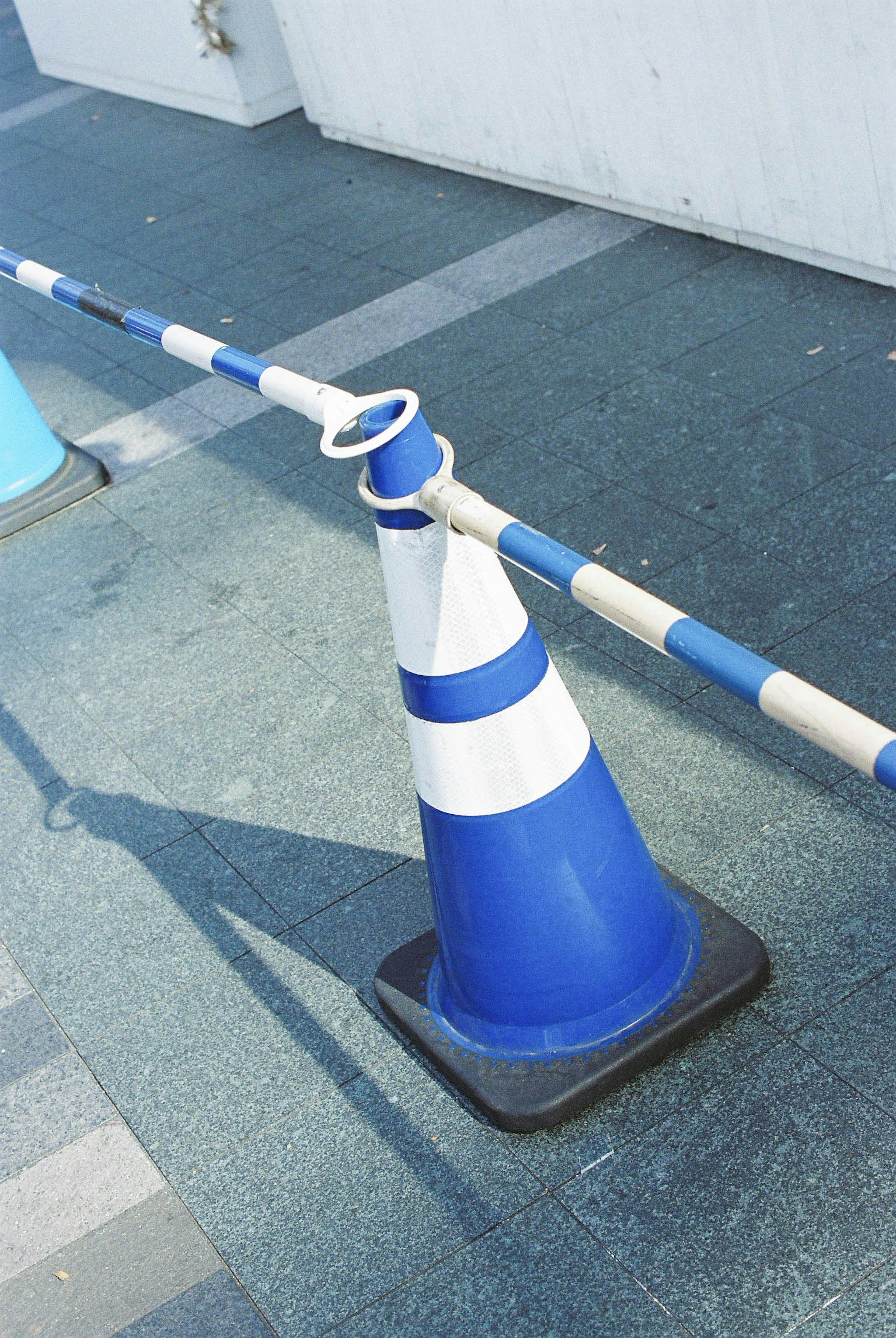 Blue and white traffic cone with a barrier on the pavement