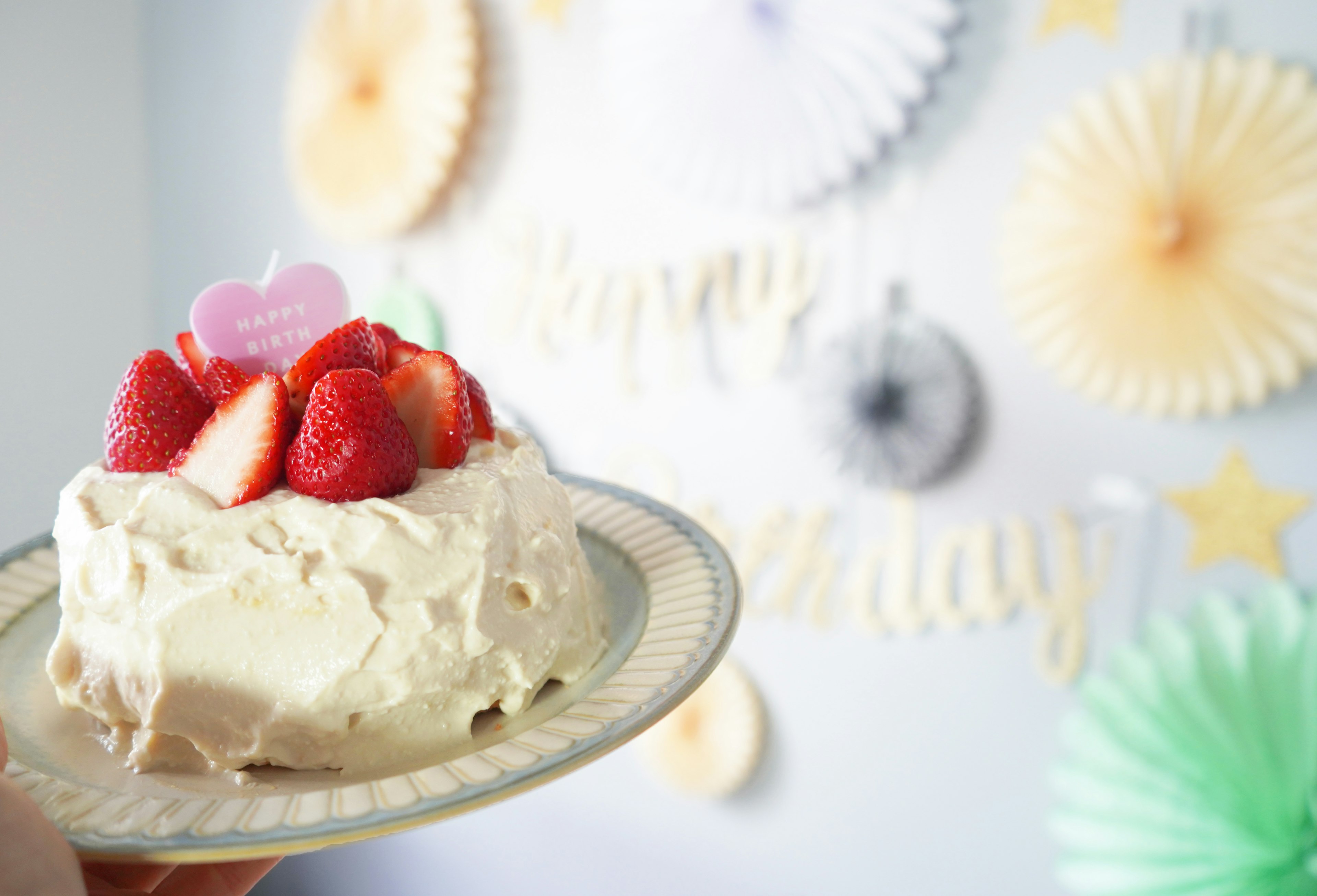 Strawberry cake on a plate with party decorations in the background