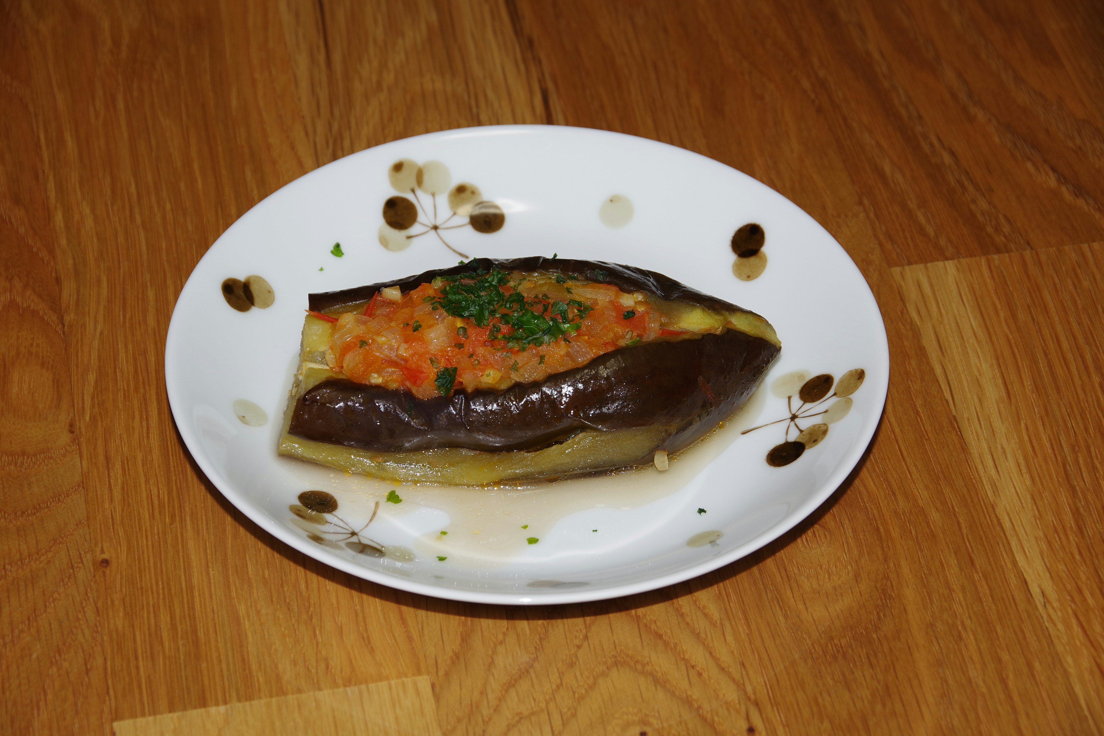 Plat d'aubergine farcie sur une assiette avec tomate et herbes