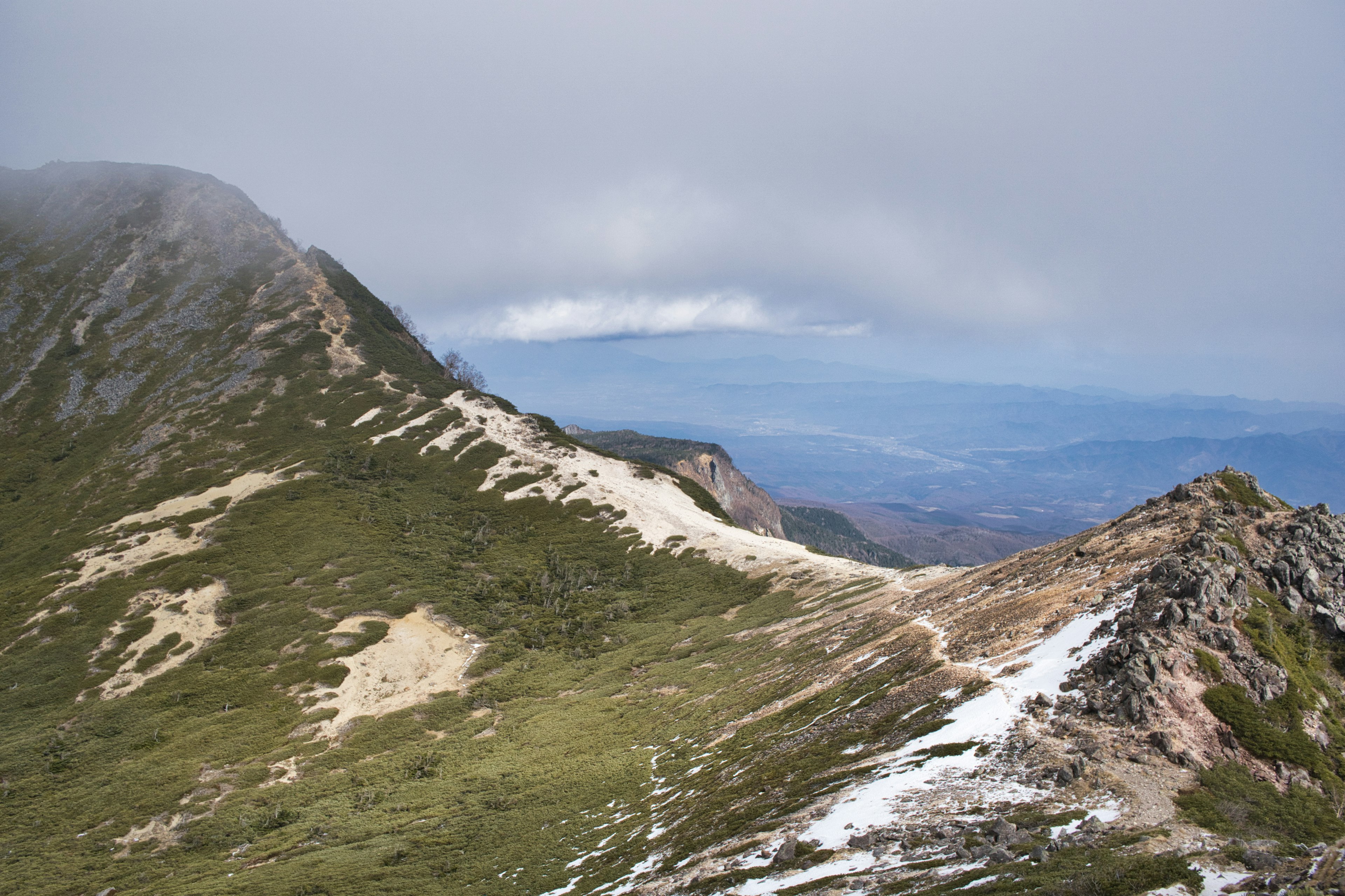 Paesaggio montano con nuvole che coprono le vette e prati verdi