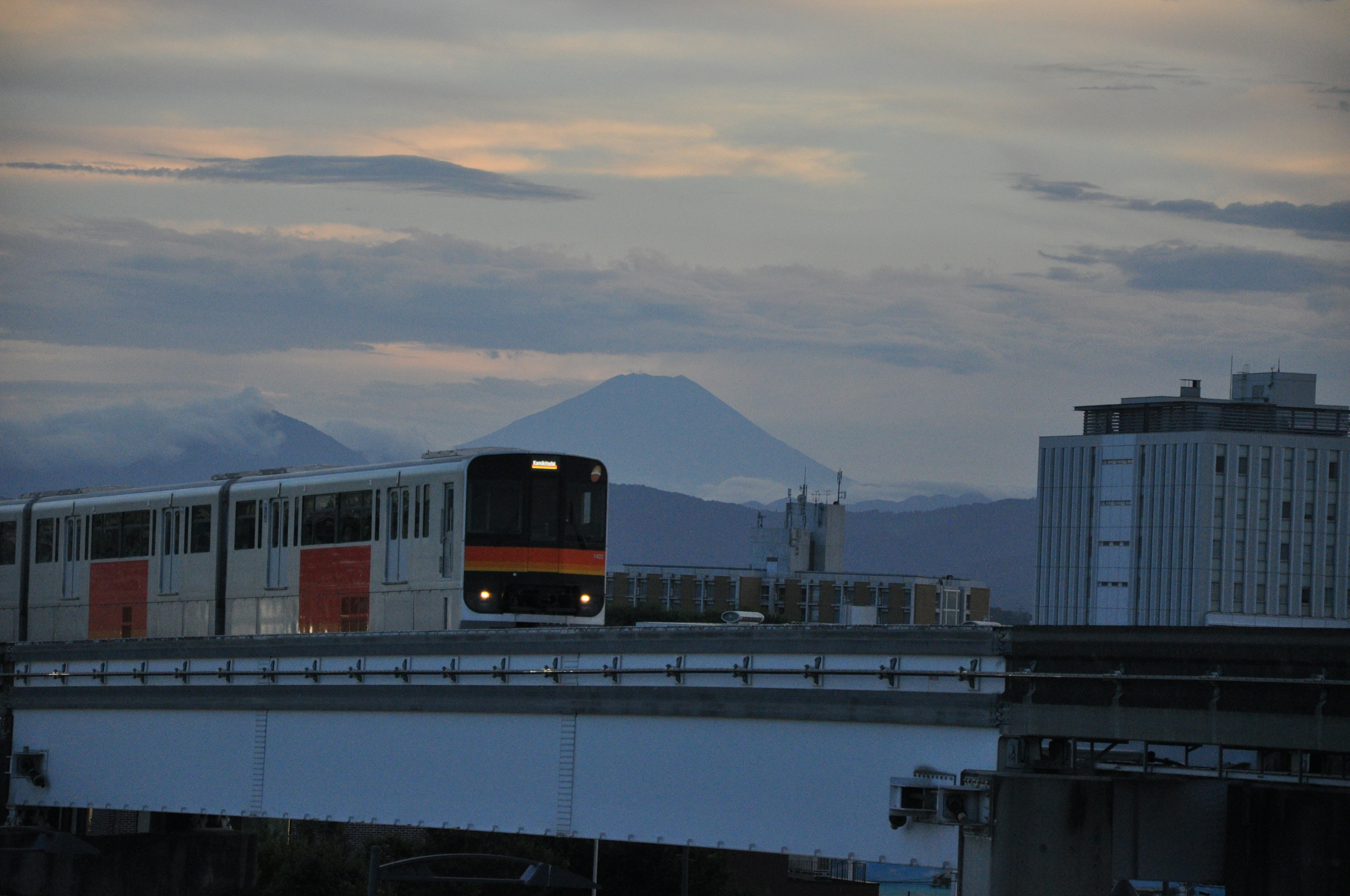 Zug, der vor dem Hintergrund eines Dämmerungshimmels und entfernten Bergen fährt