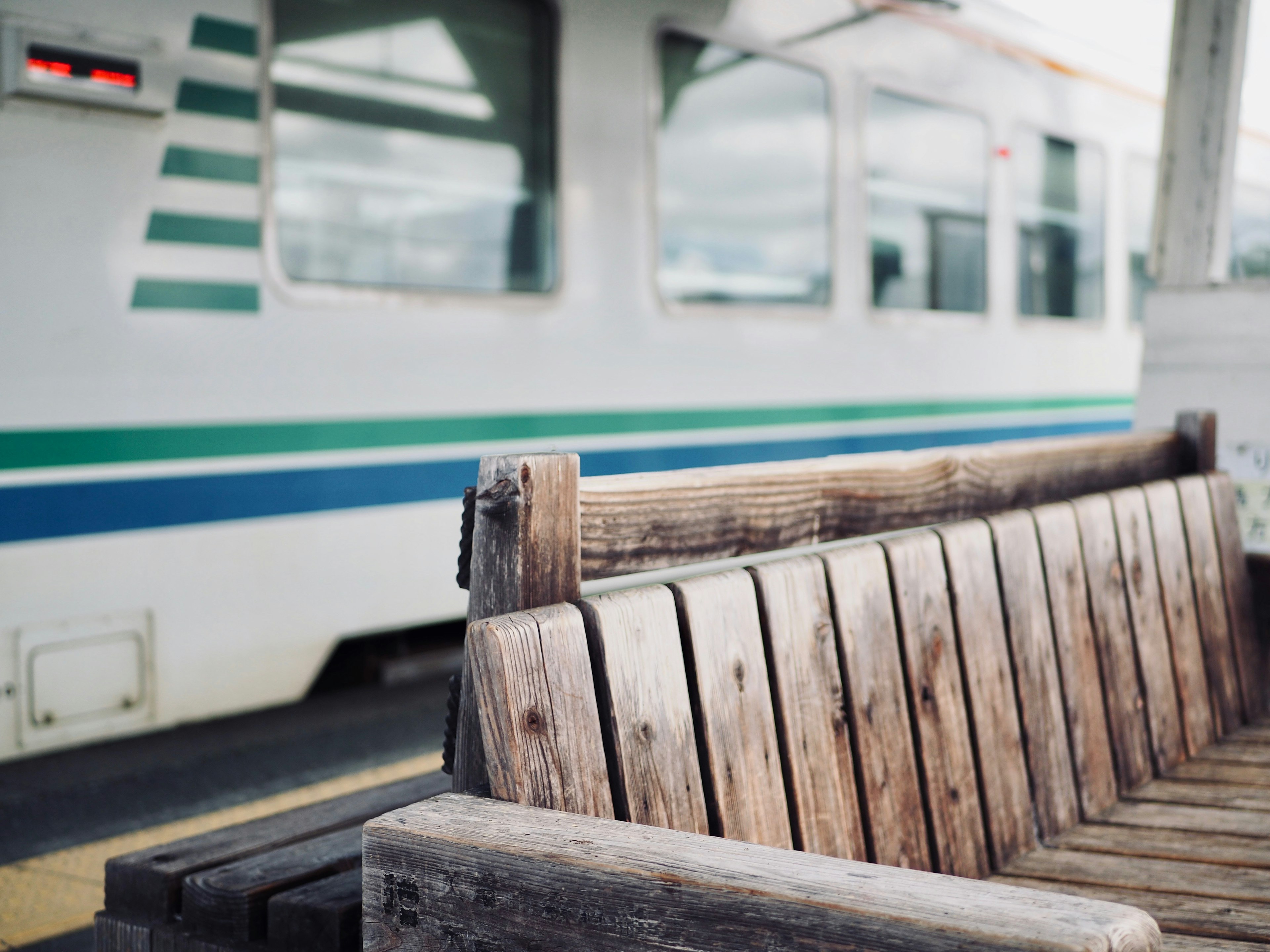 Bangku kayu dengan bagian kereta terlihat di latar belakang di stasiun