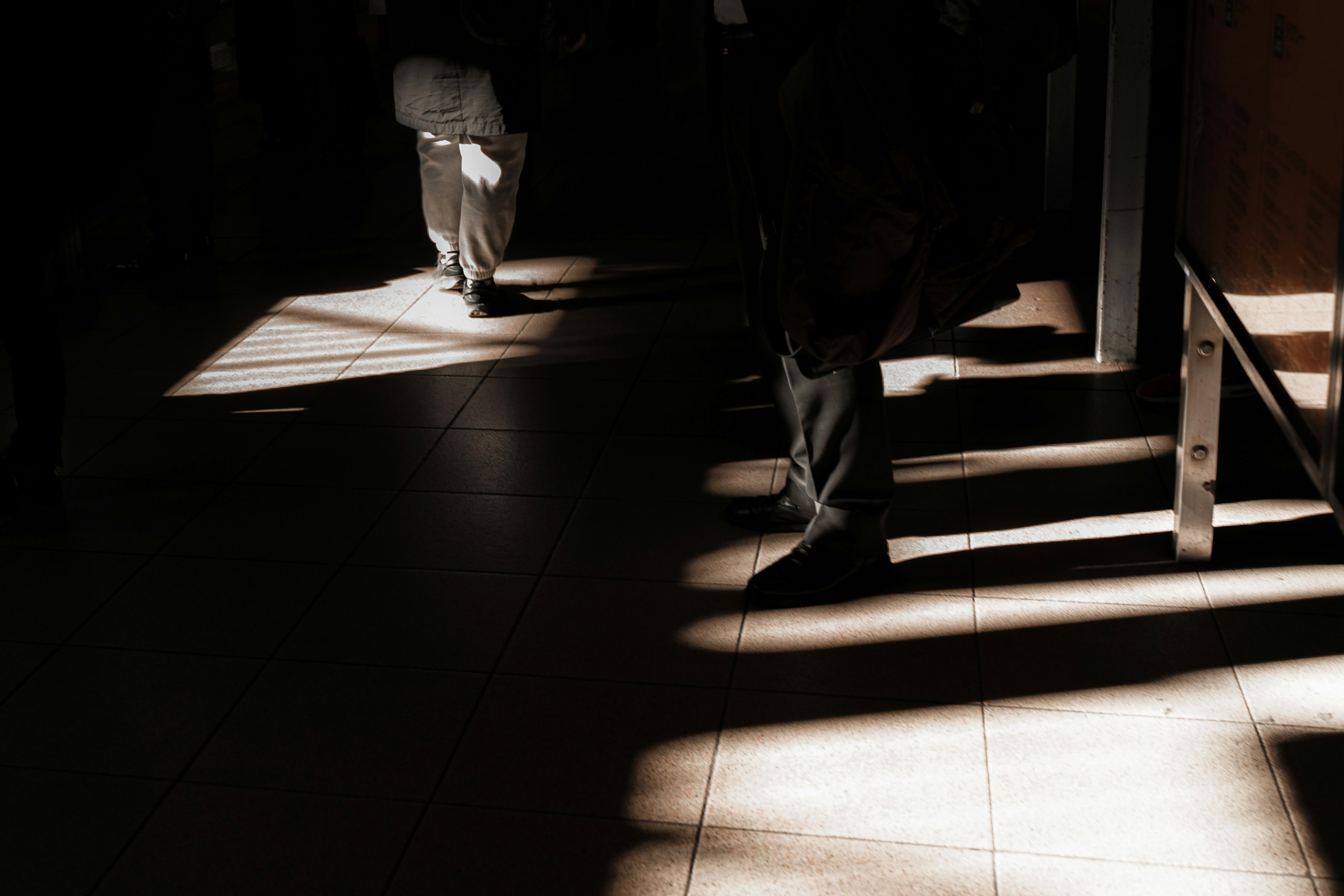 Silhouetted figure walking in a dimly lit space with contrasting light