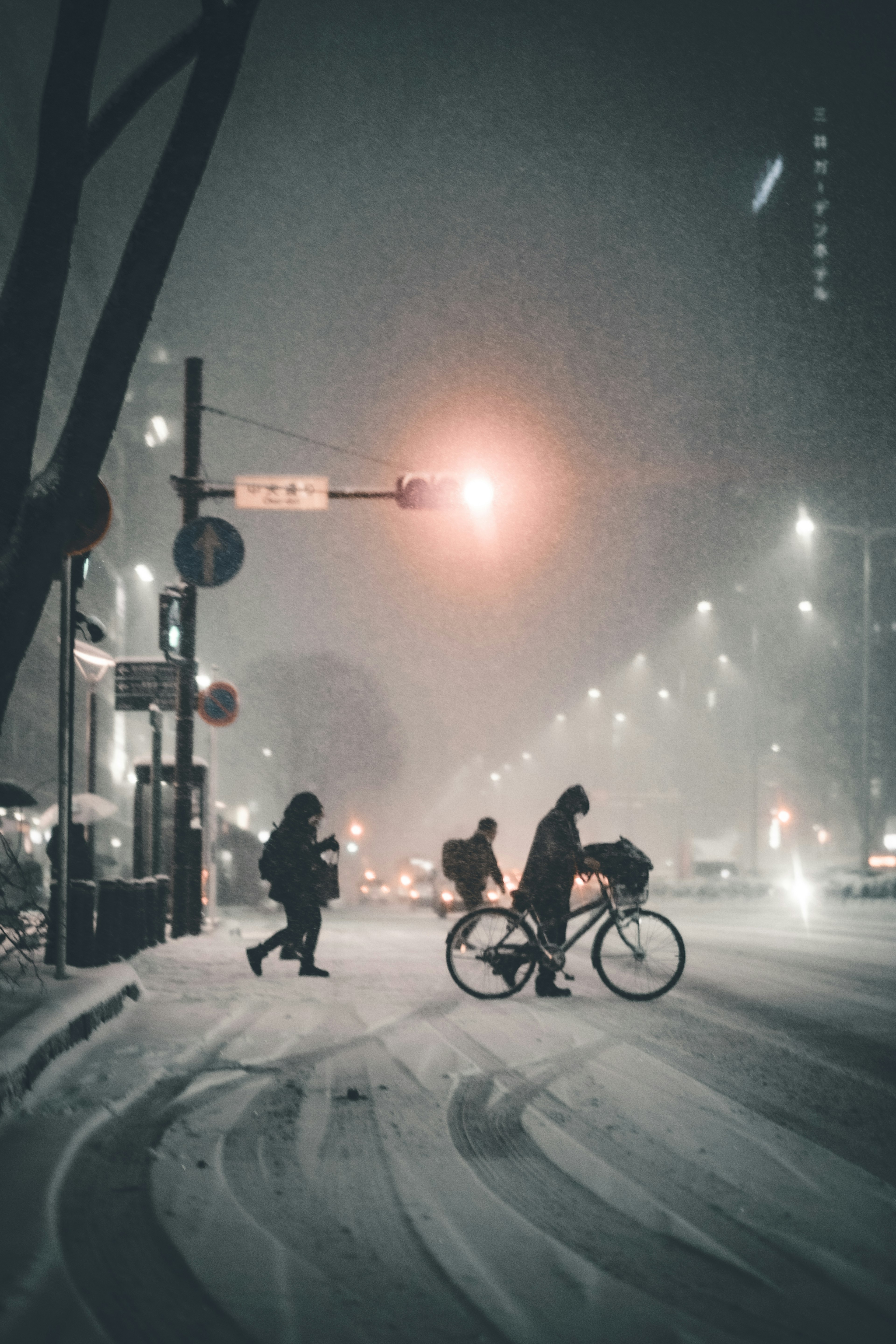 Menschen, die im Schnee gehen, mit einem Radfahrer an einer Straßenkreuzung