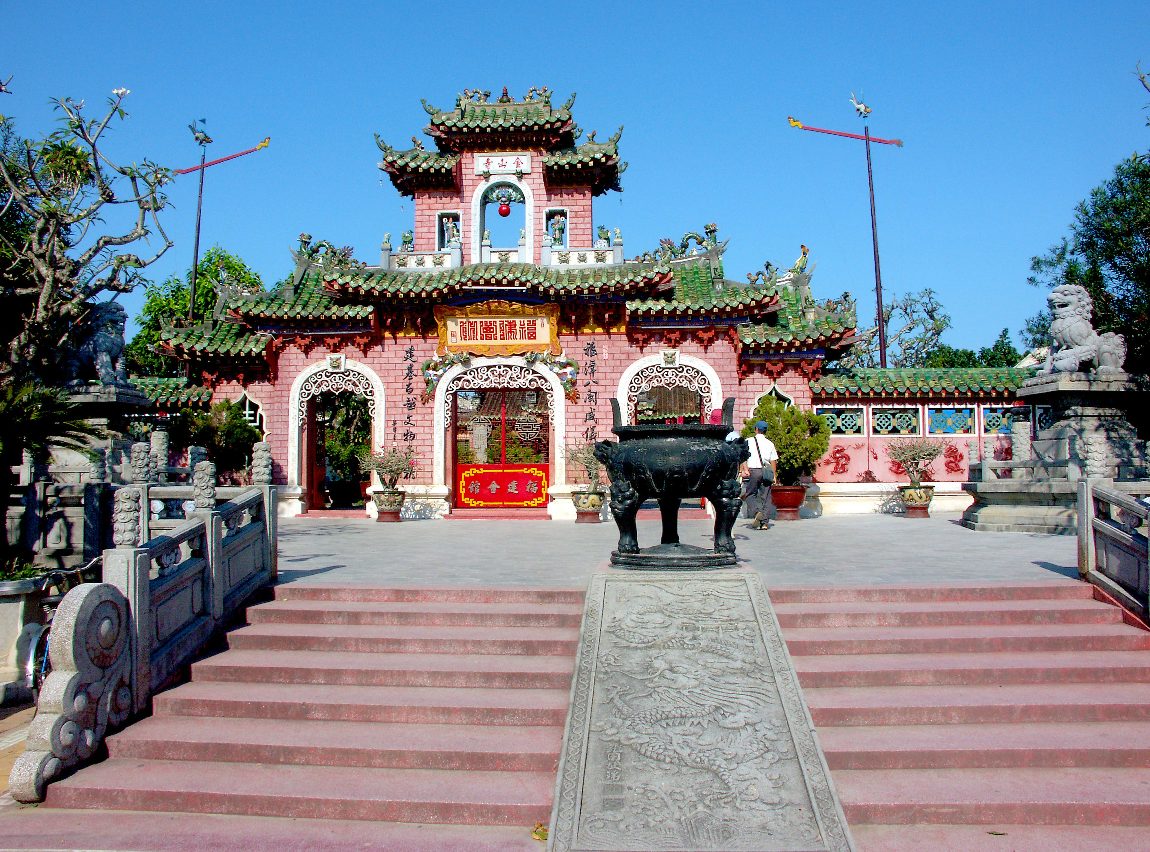 Beautiful Chinese temple exterior with red walls and decorative roof steps leading up to the entrance stone sculptures on either side