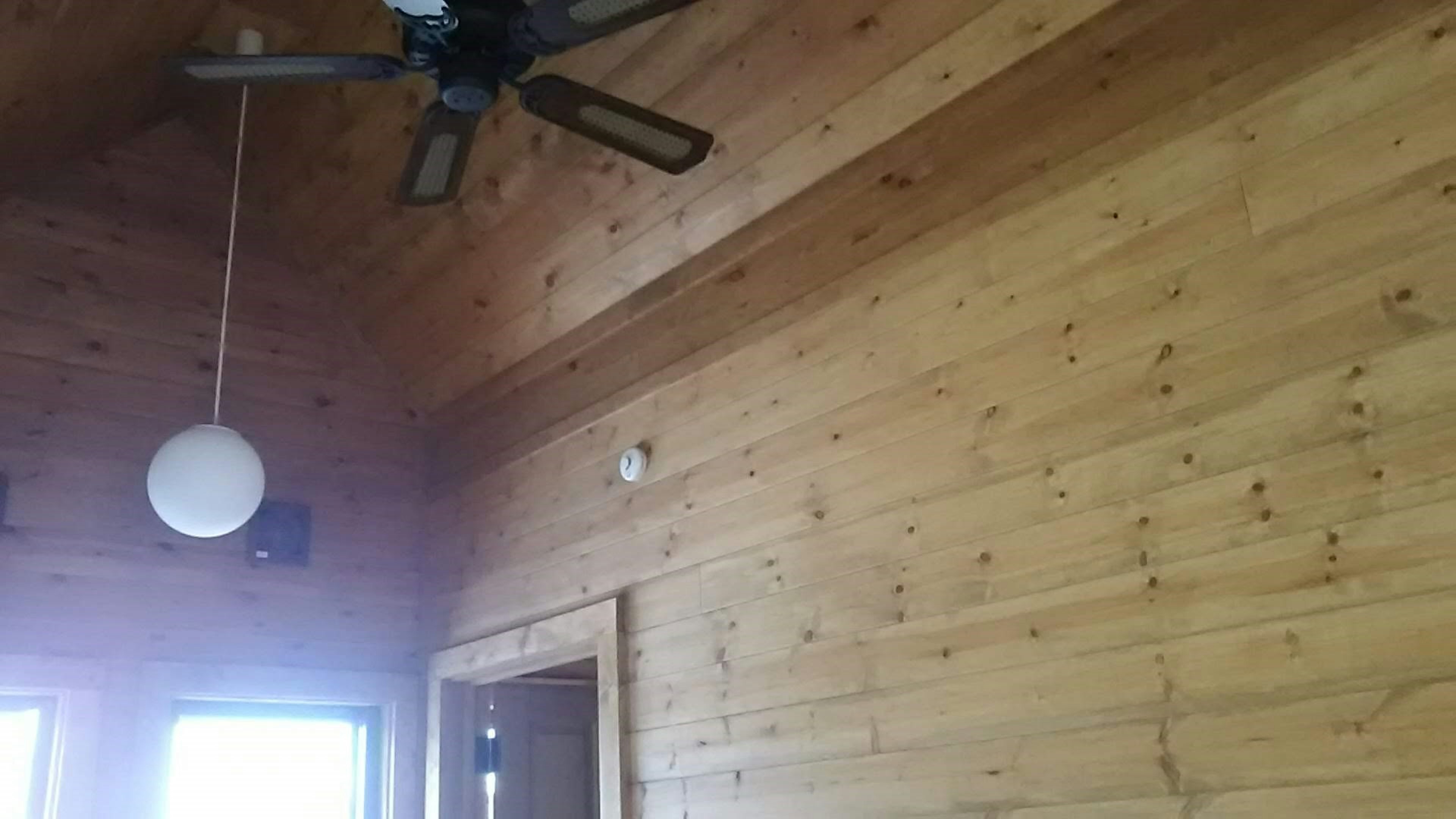 Intérieur d'une pièce avec des murs en bois et un ventilateur de plafond