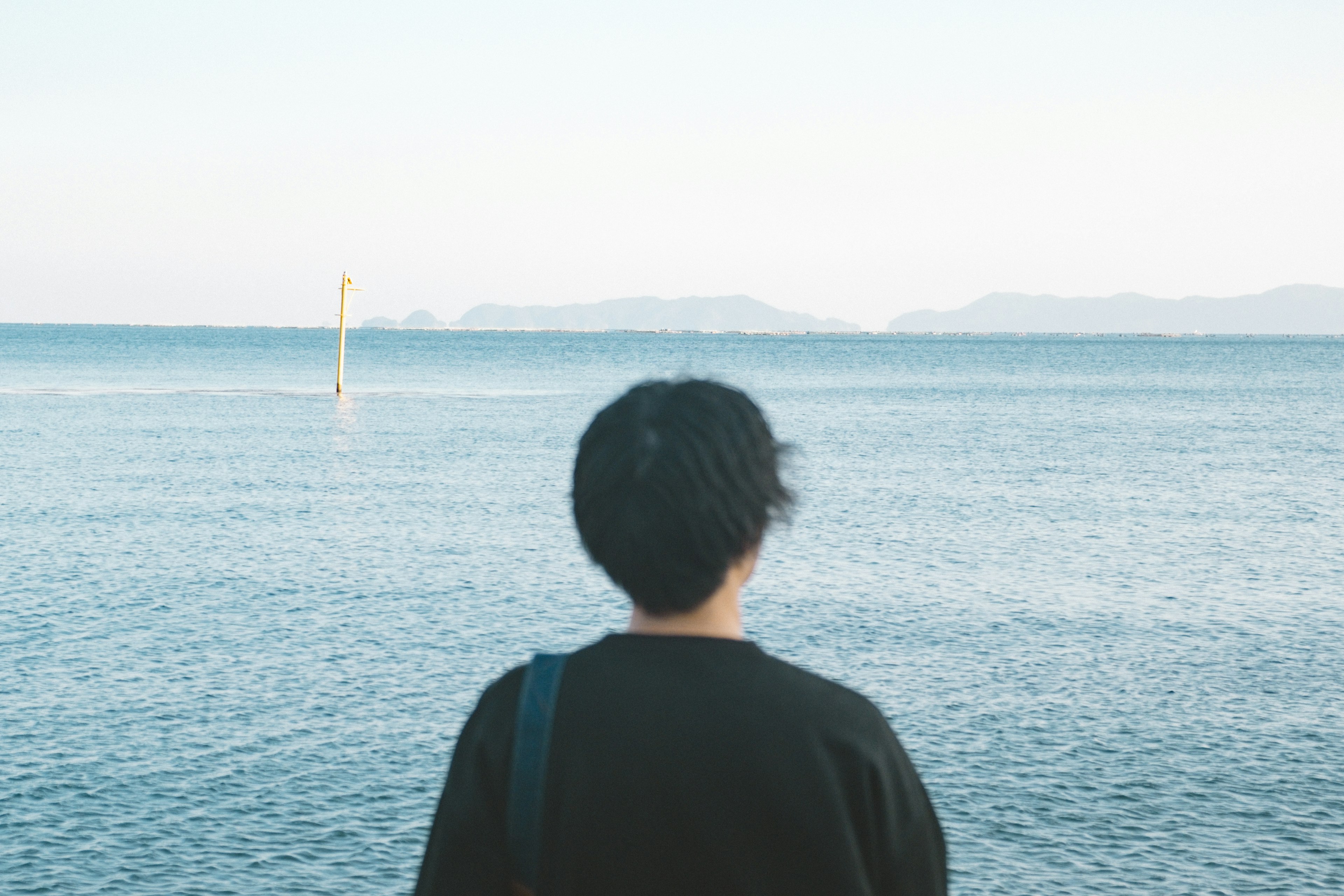 Person gazing at the sea from behind