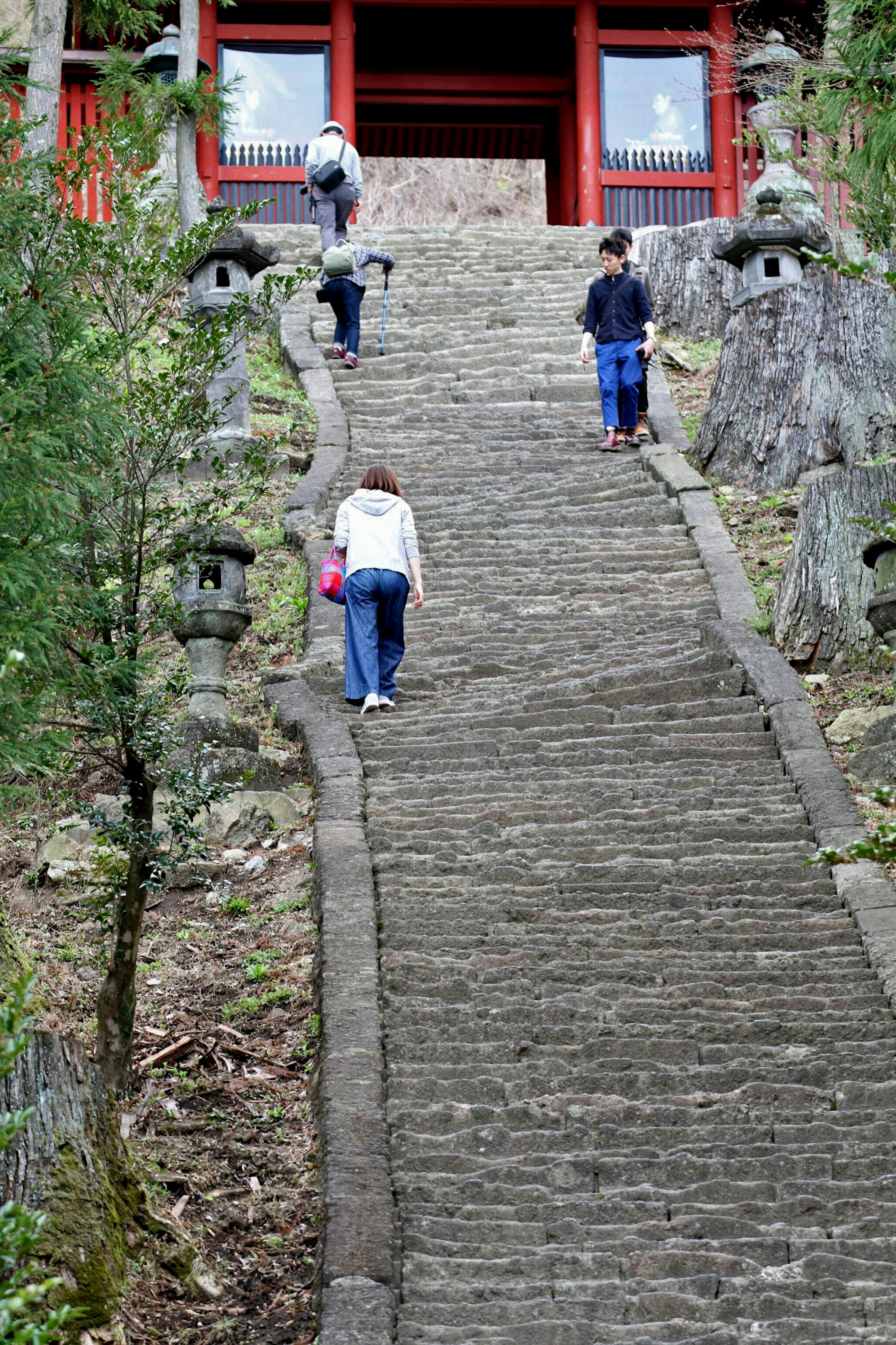 People climbing a stone staircase with lanterns on either side