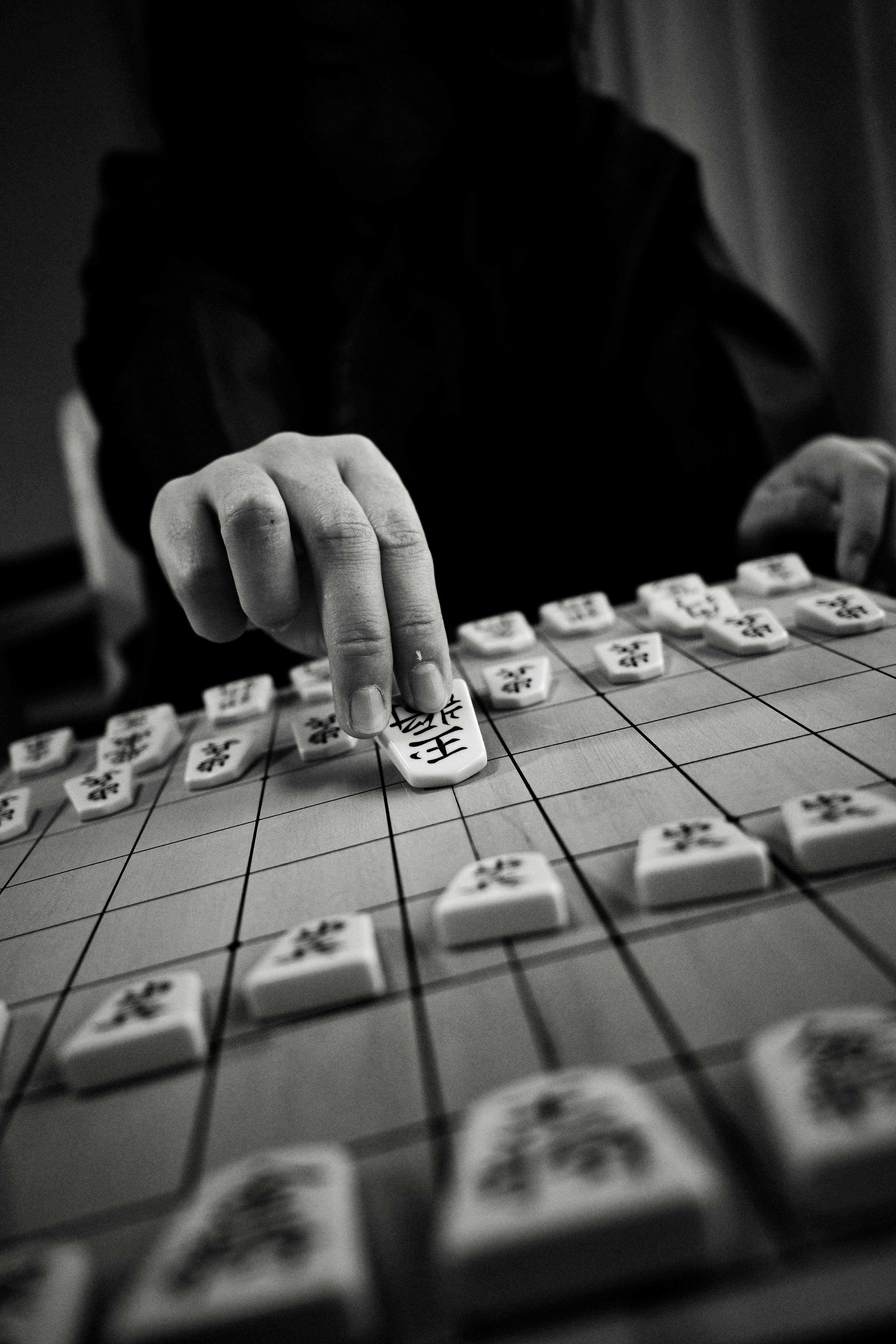 Eine Hand bewegt Mahjong-Steine auf einem Spielbrett