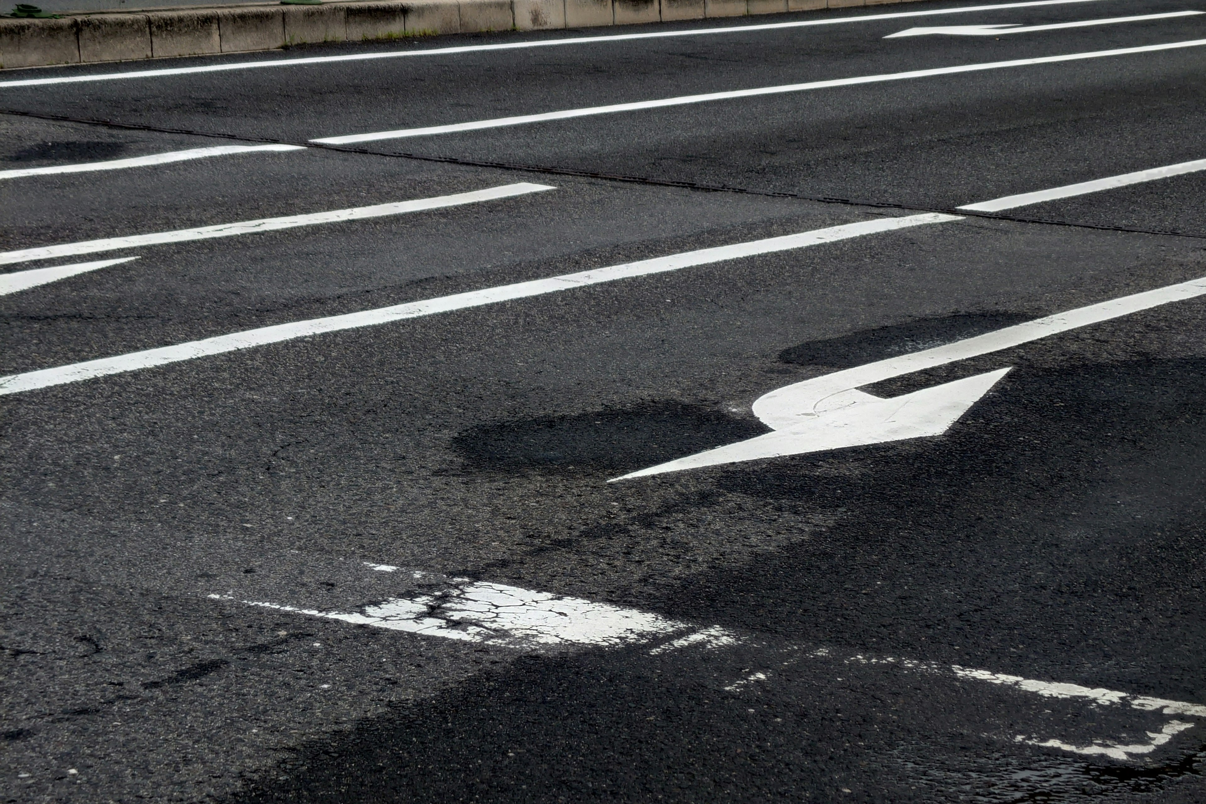 Carretera de asfalto negro con flechas y líneas blancas