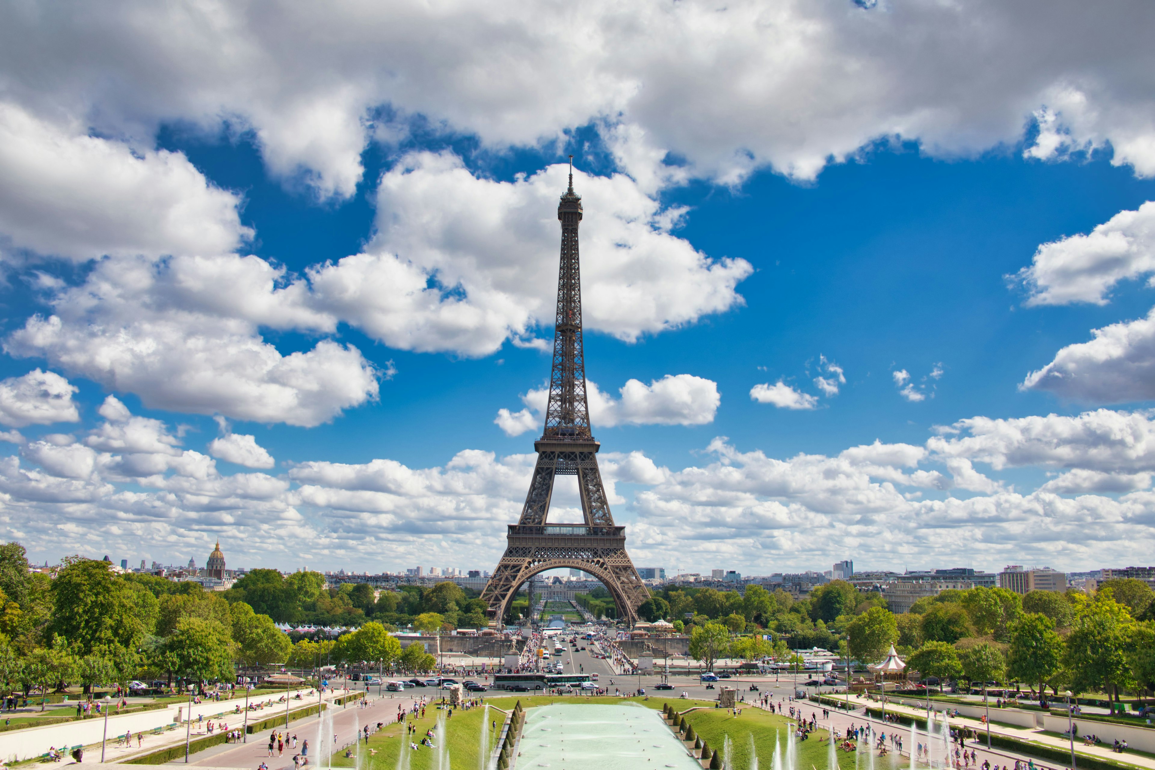 Torre Eiffel bajo un cielo azul brillante con nubes esponjosas