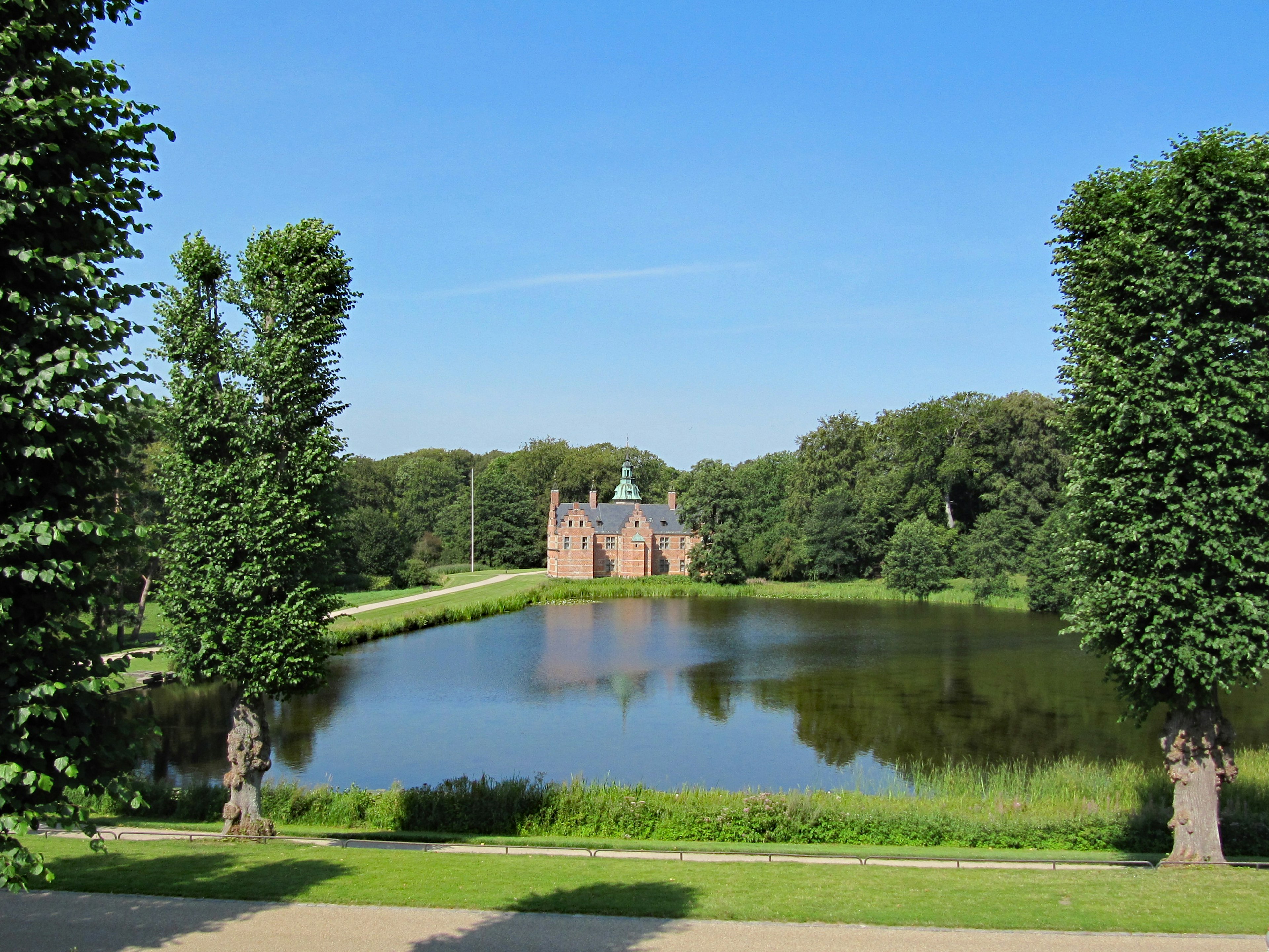 Historic building surrounded by lush park and serene pond