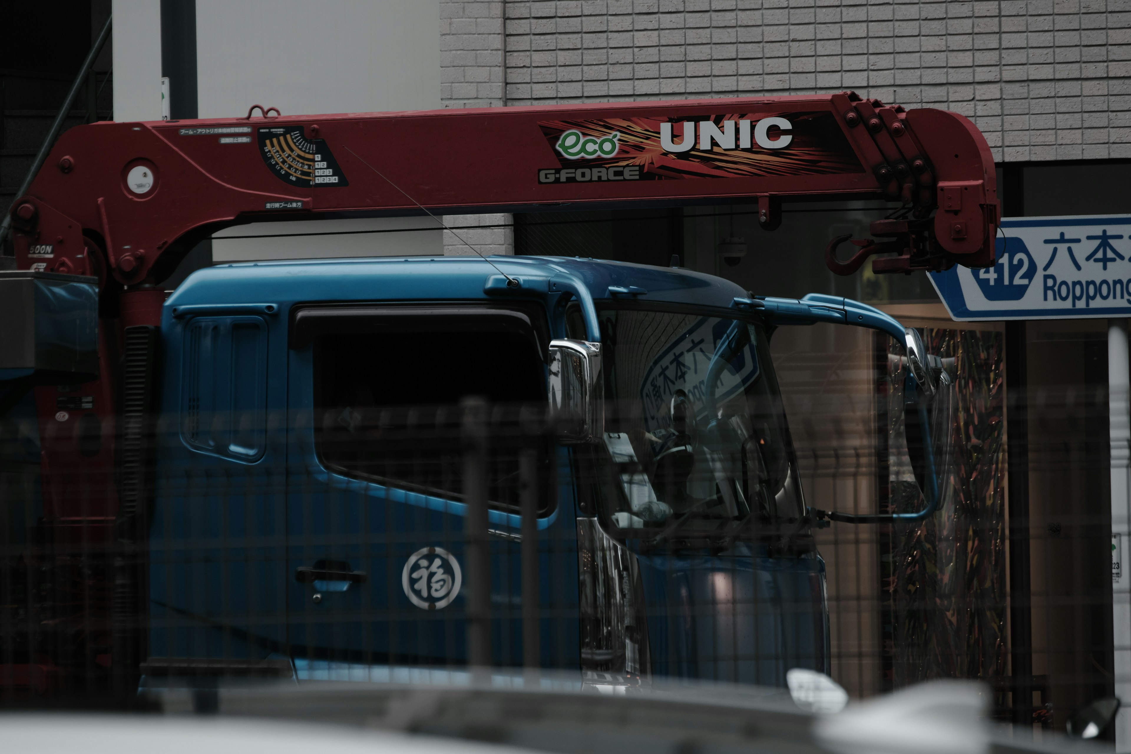 Camion blu con un braccio di gru rosso in un cantiere