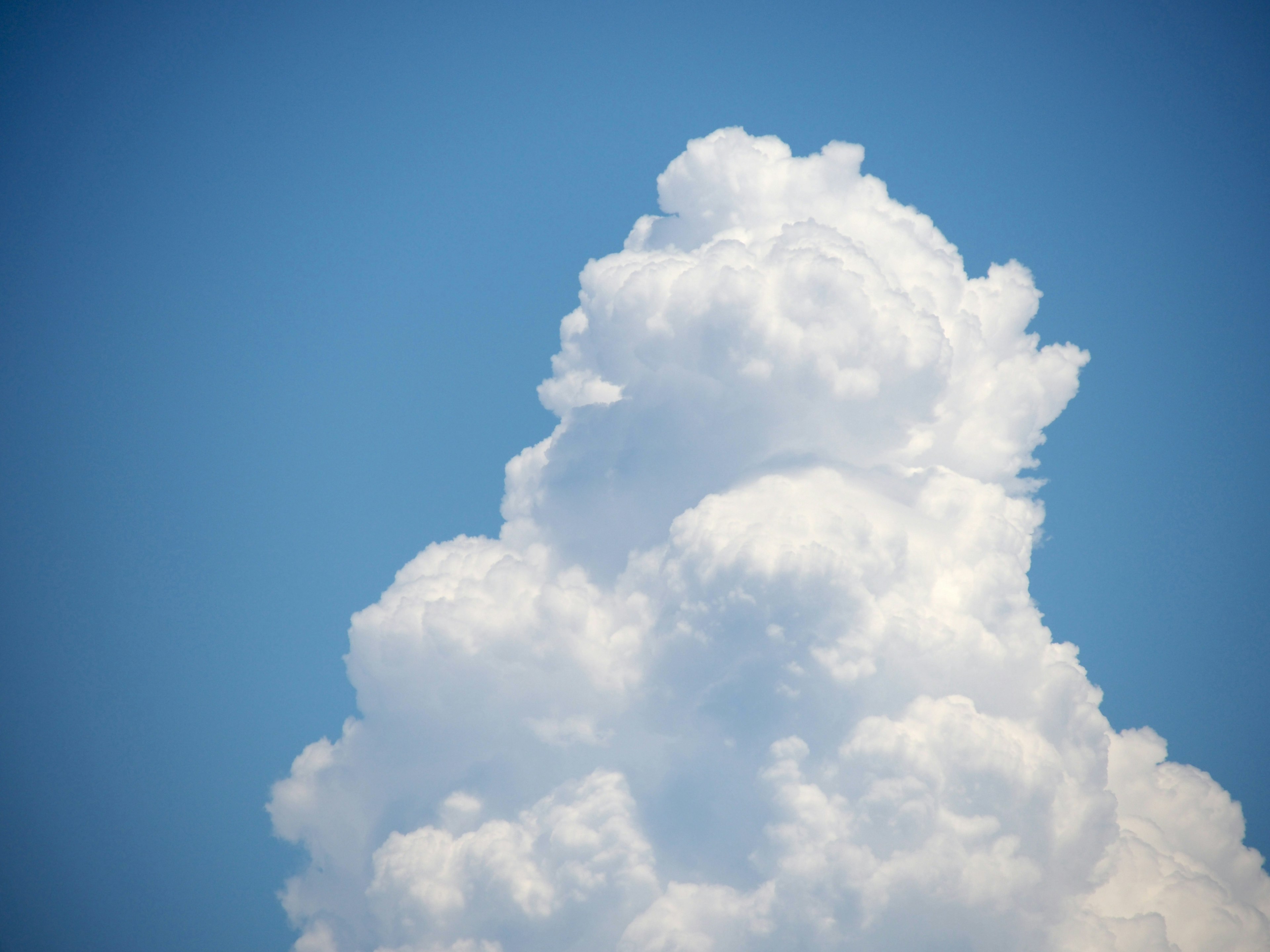 Awan cumulus putih berbulu di latar belakang langit biru