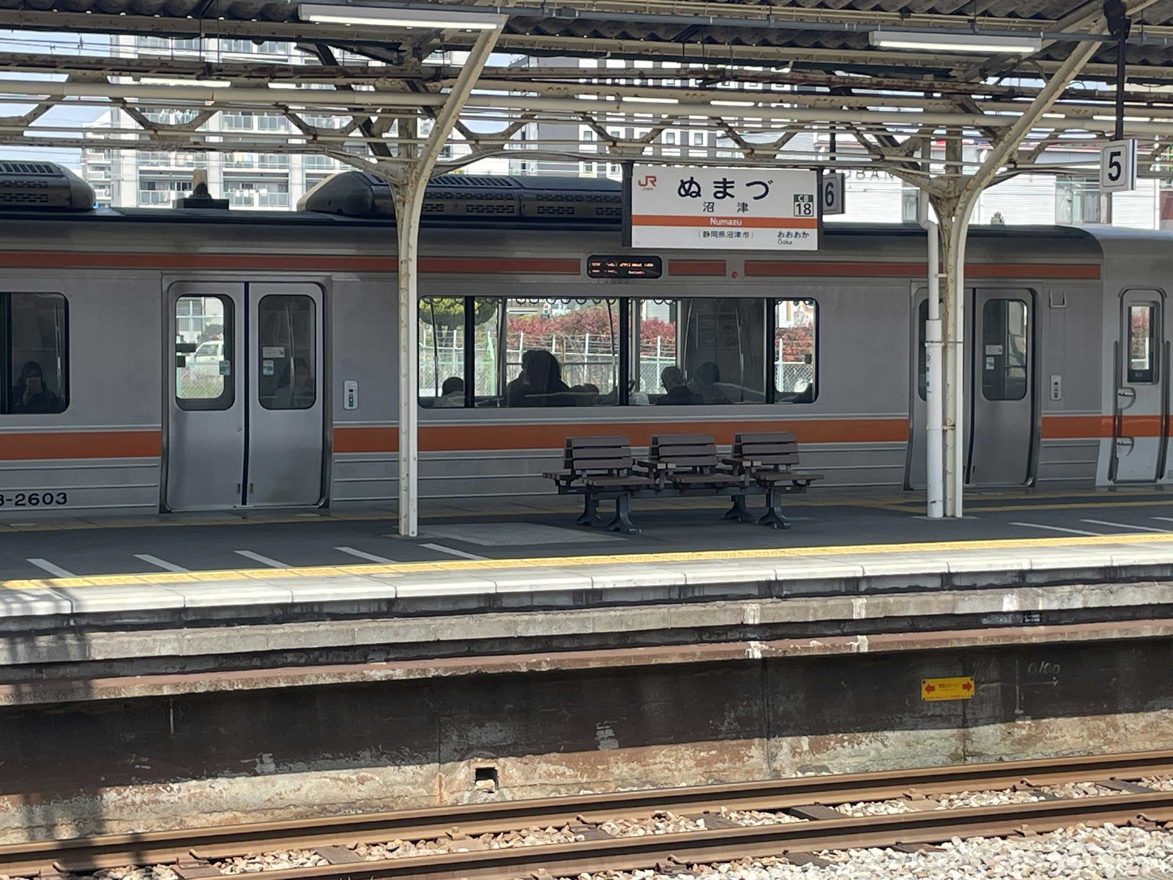 Train stopped at a station platform with a bench