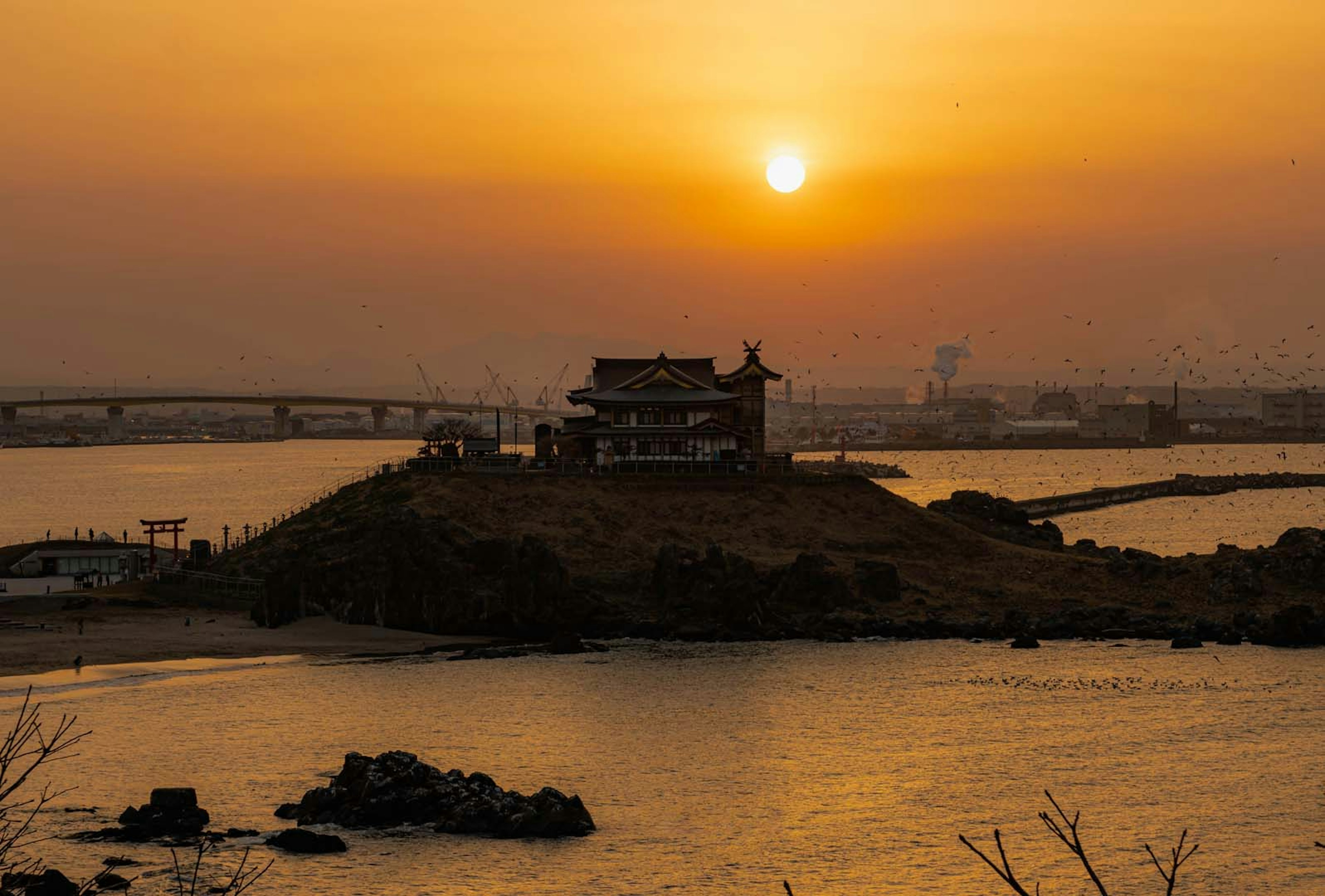 Haus auf einer Insel mit Sonnenuntergang und ruhiger Wasseroberfläche