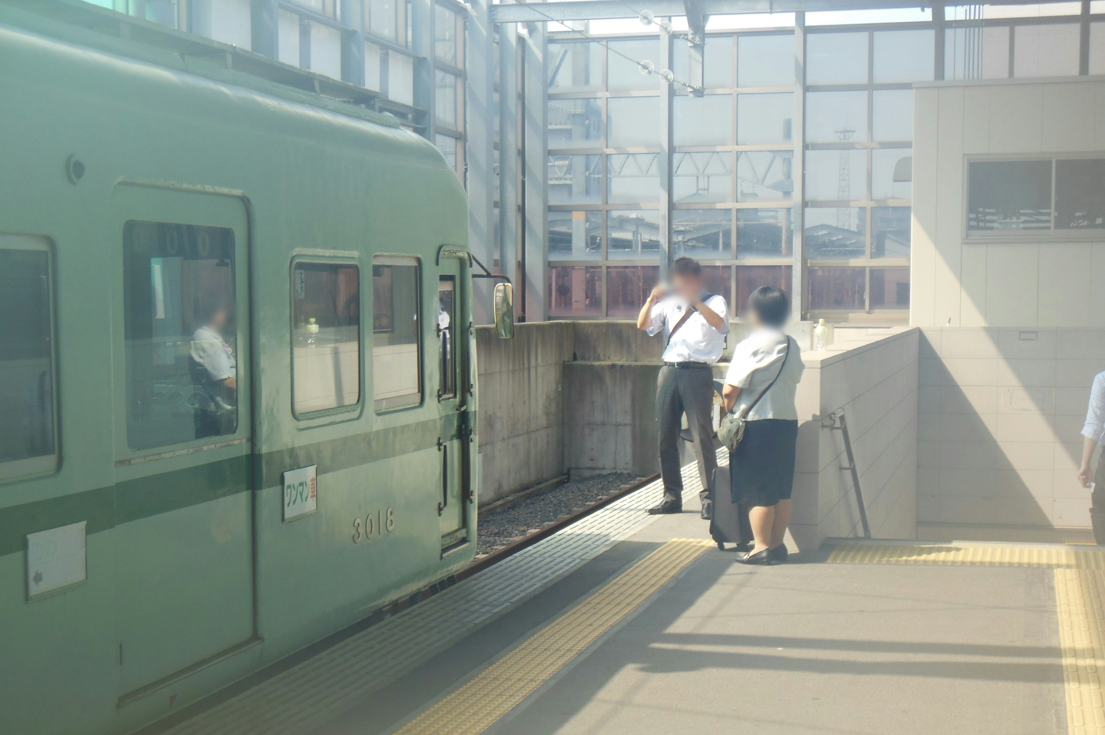 Green train at a station with passengers