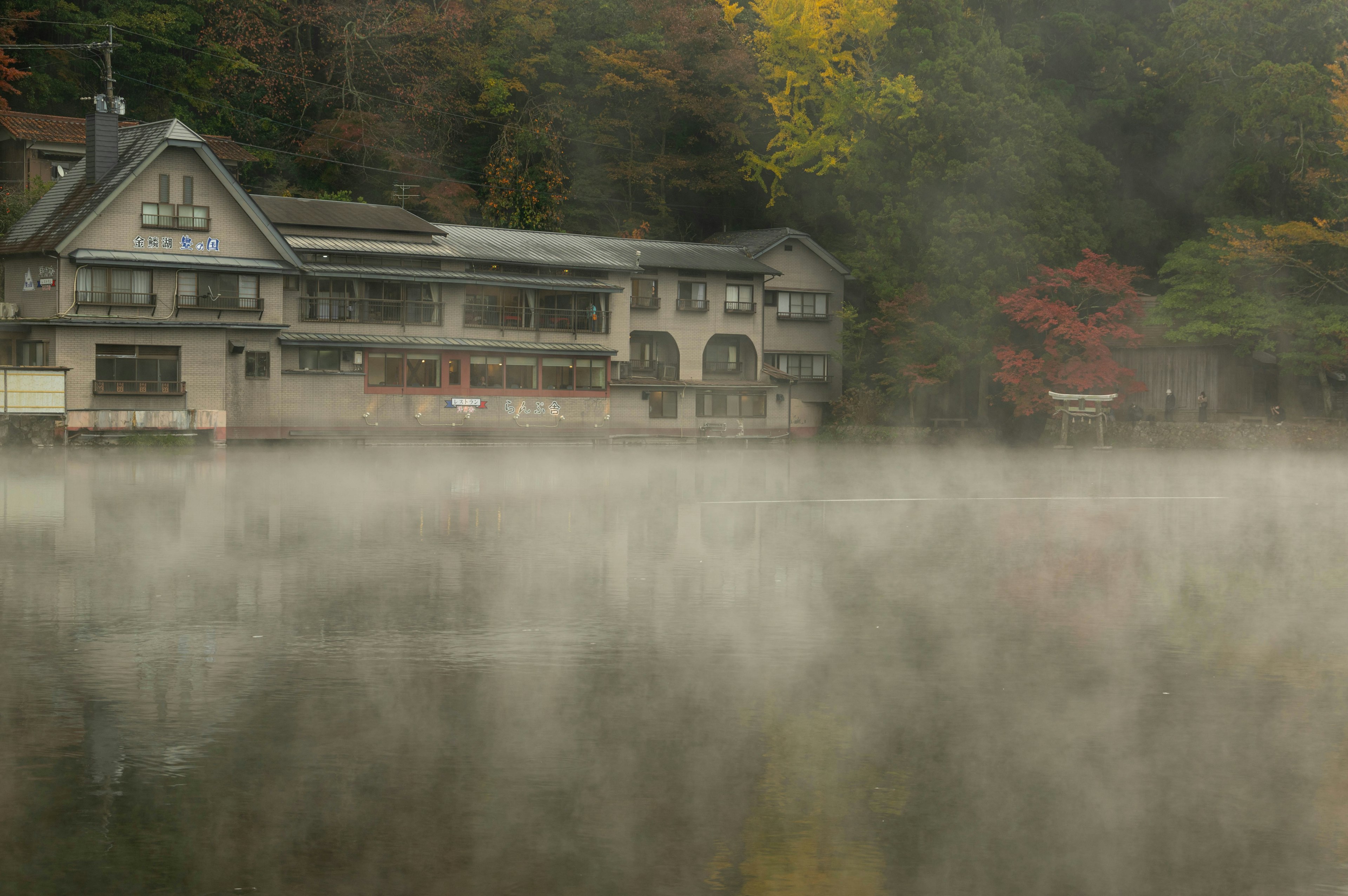 Vue scénique d'un ancien hôtel près d'un lac brumeux entouré de feuillage d'automne