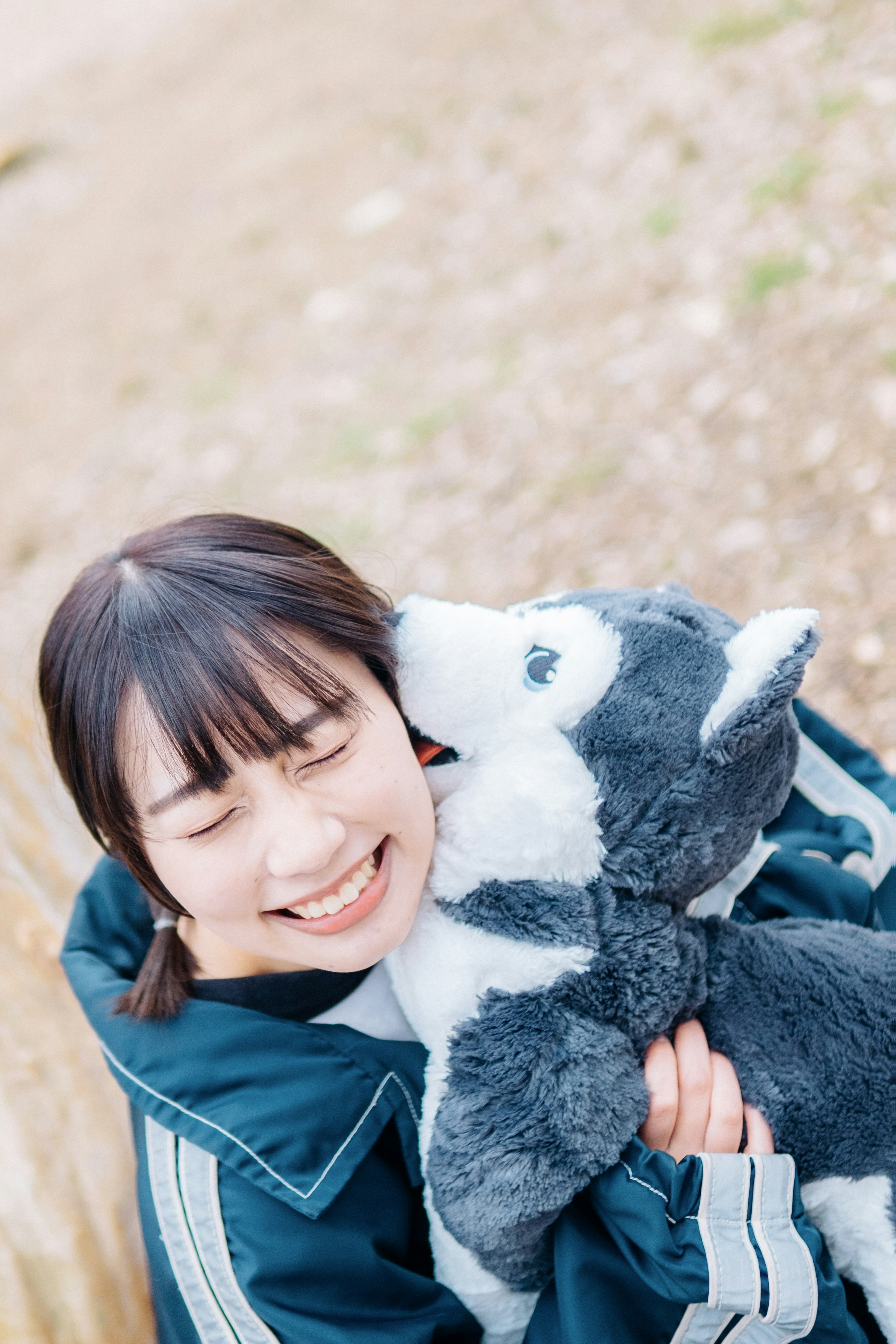 Une femme souriante tenant un jouet en peluche de chien gris