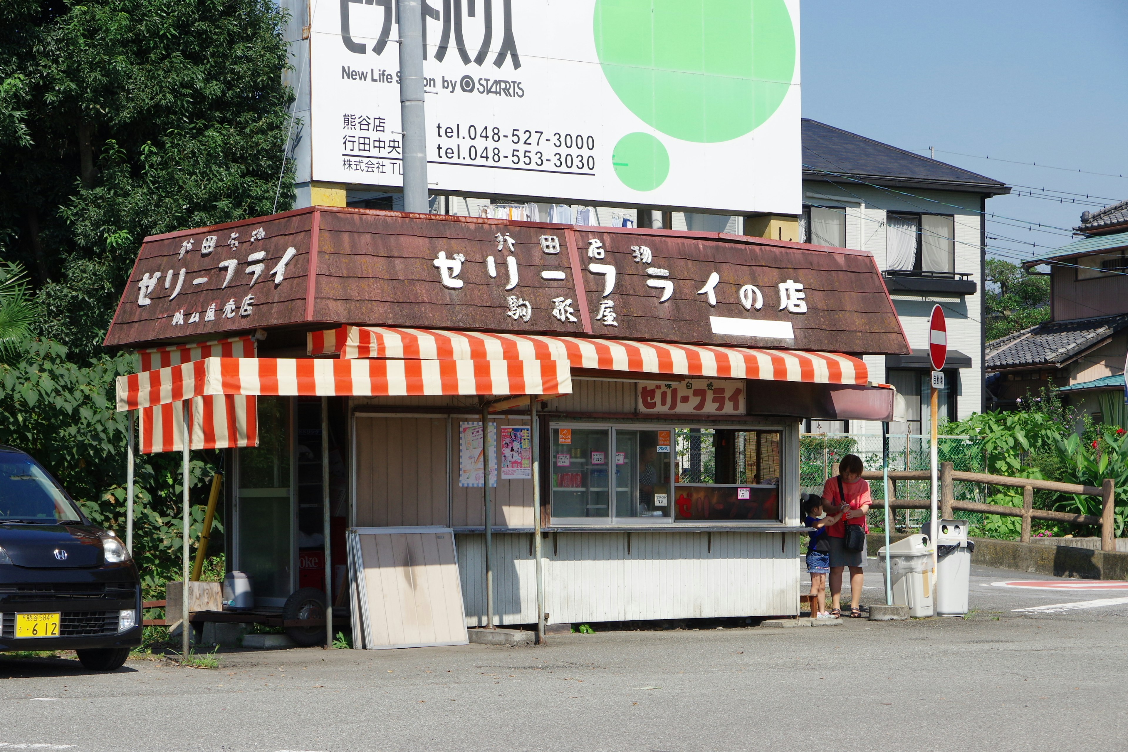 小食品攤外觀，橙白條紋遮陽篷