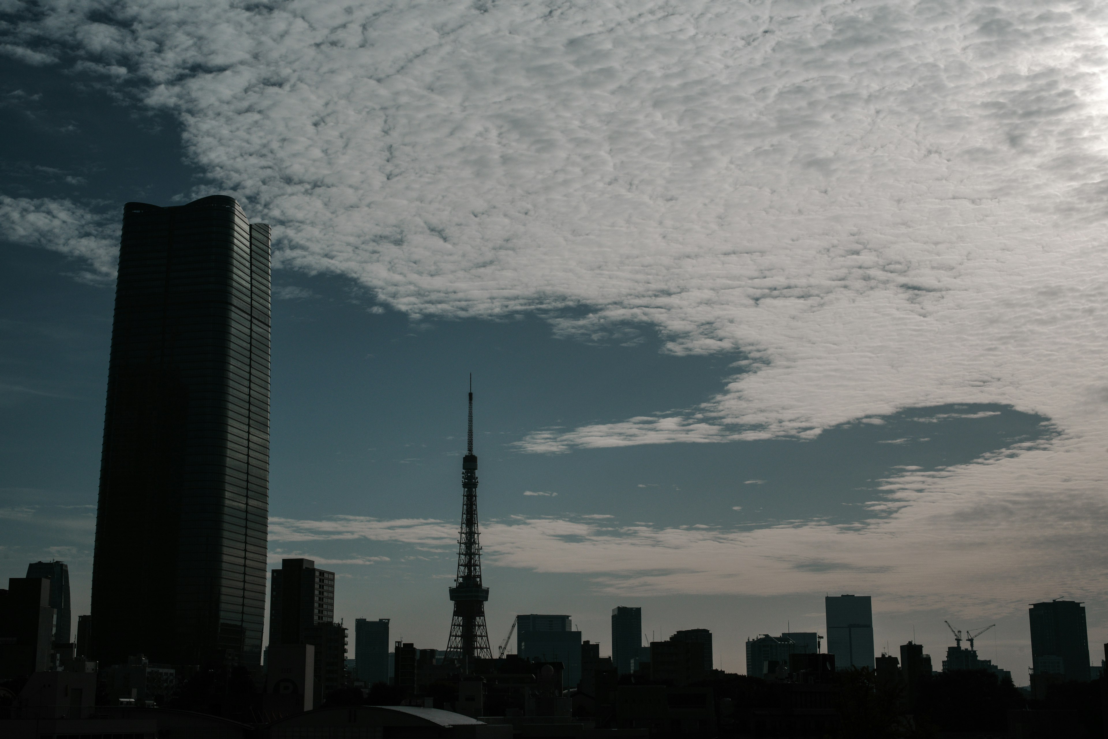 Tokyo skyline featuring a towering skyscraper and Tokyo Tower against a backdrop of beautiful clouds