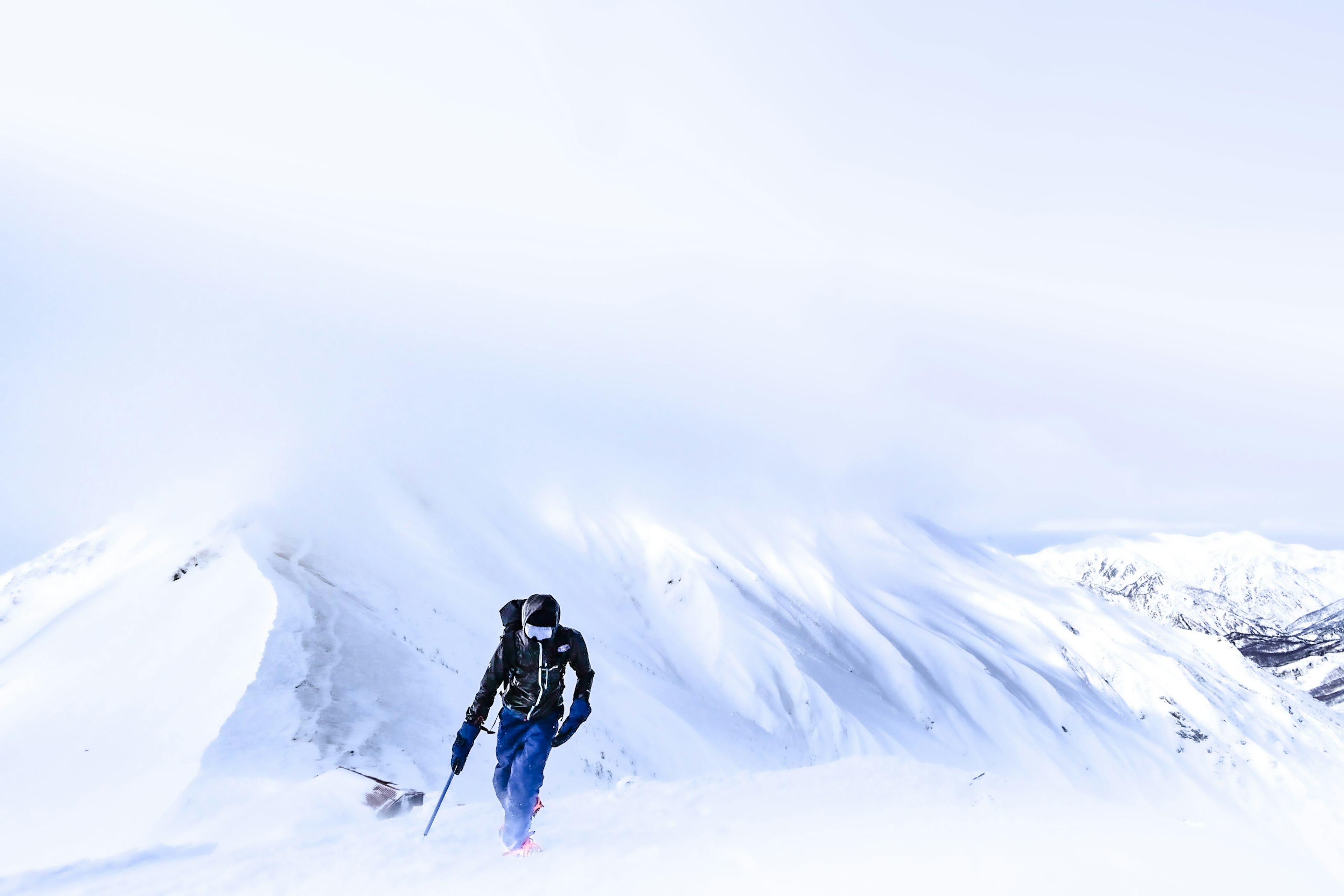 Silhouette of a climber ascending a snowy mountain with a cloudy sky