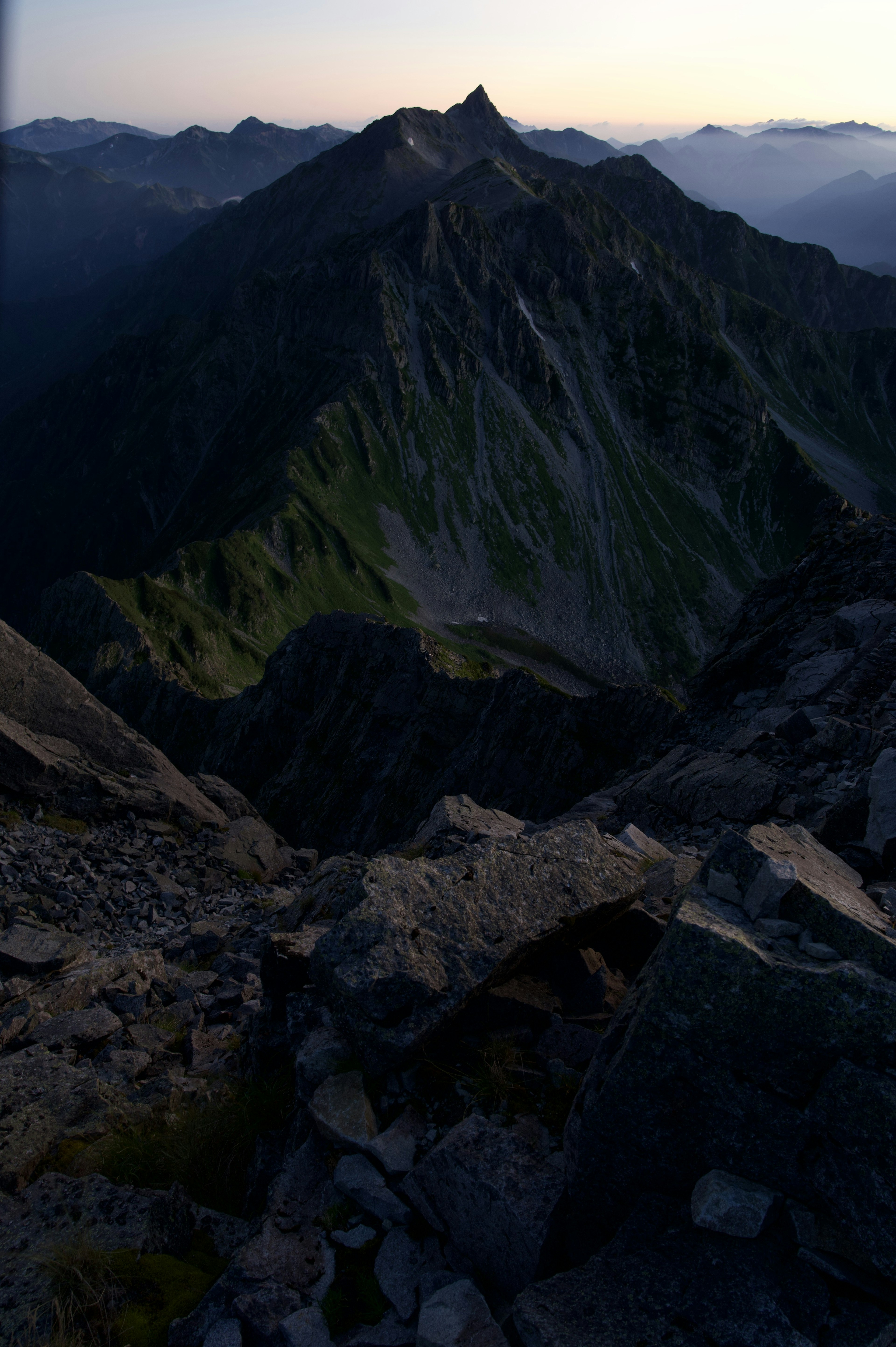 View from the mountain peak featuring green slopes and rocky terrain