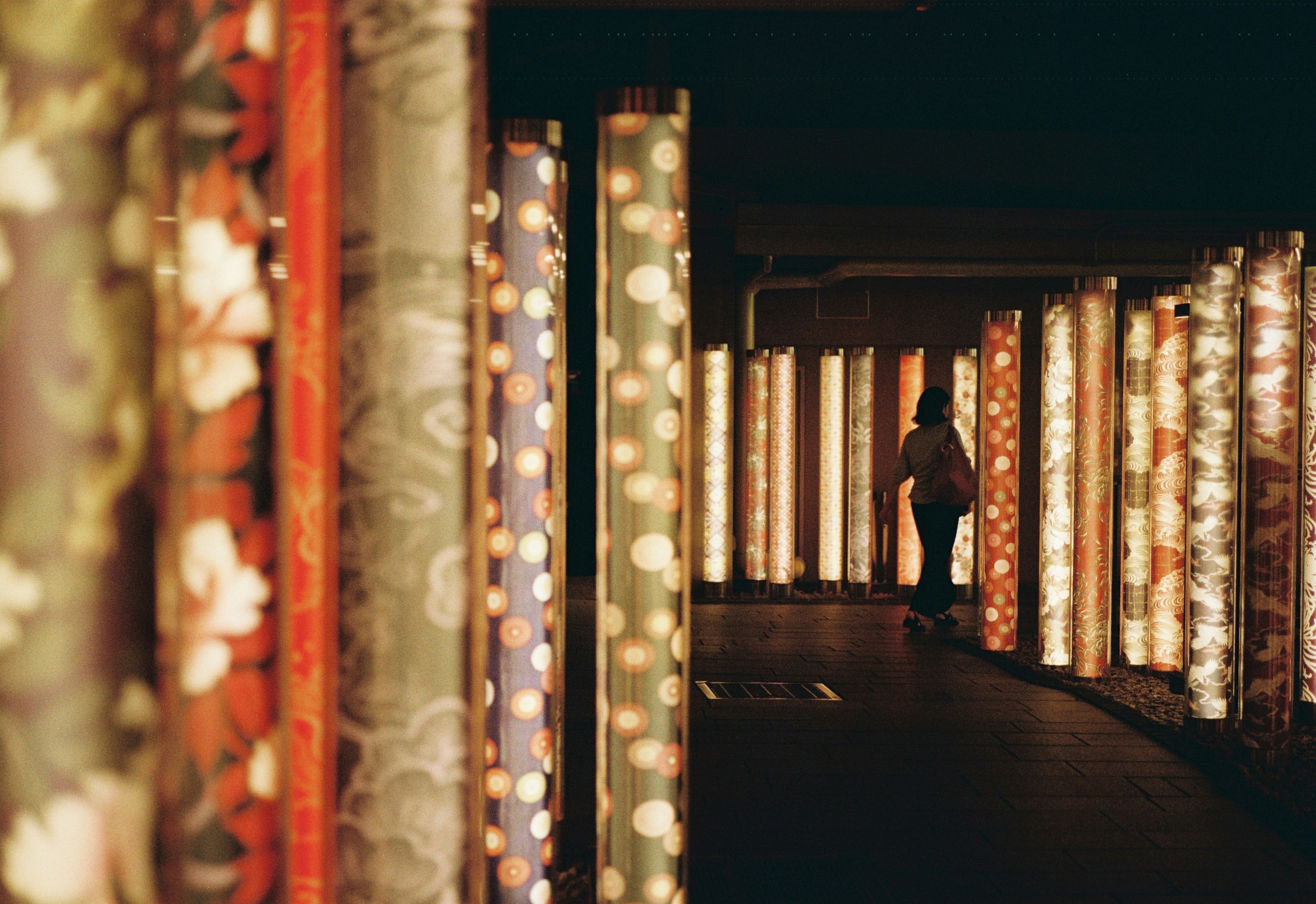 A person walking through a corridor surrounded by colorful illuminated panels