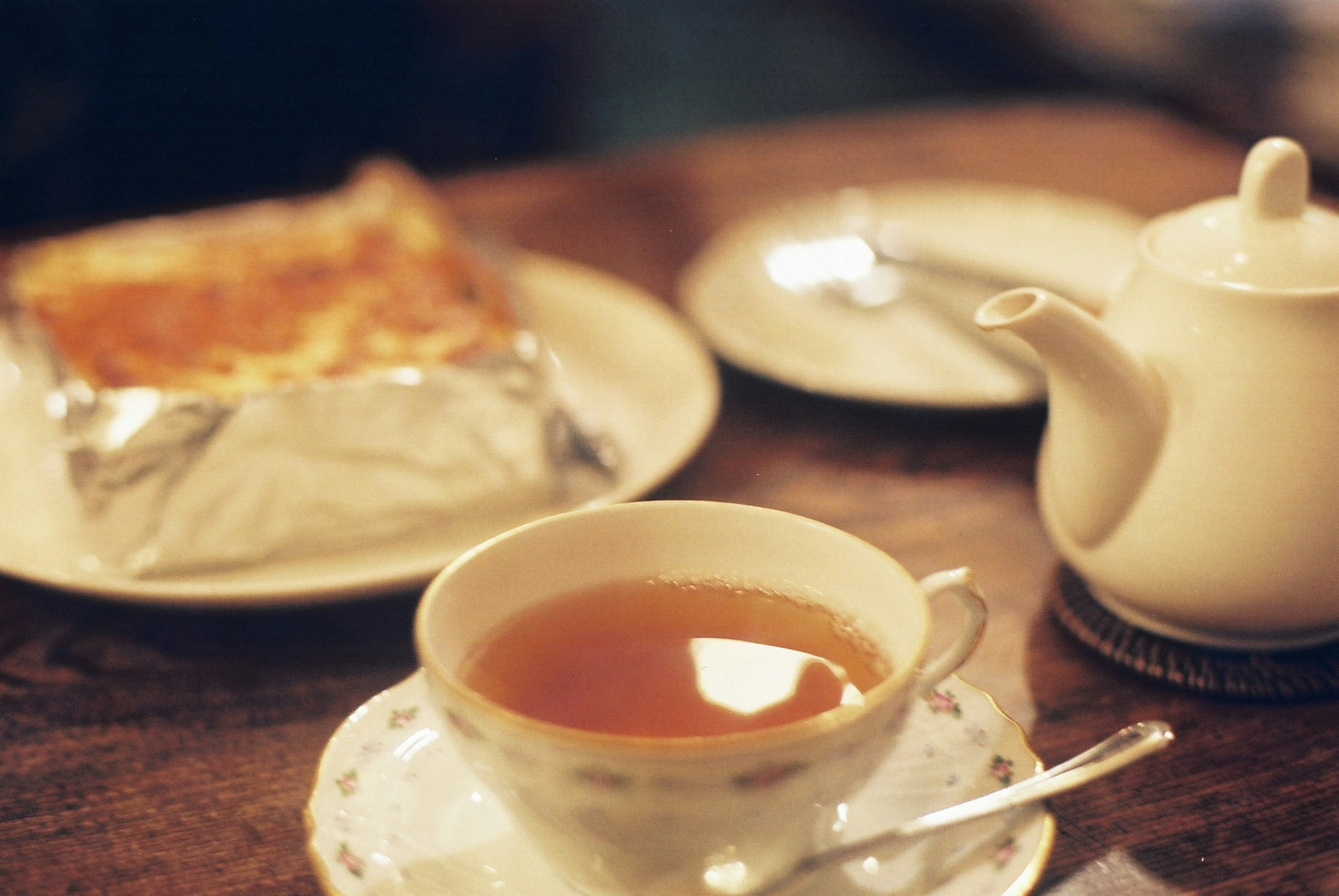 Scène de table avec une tasse de thé et une théière accompagnées d'une assiette de pâtisseries