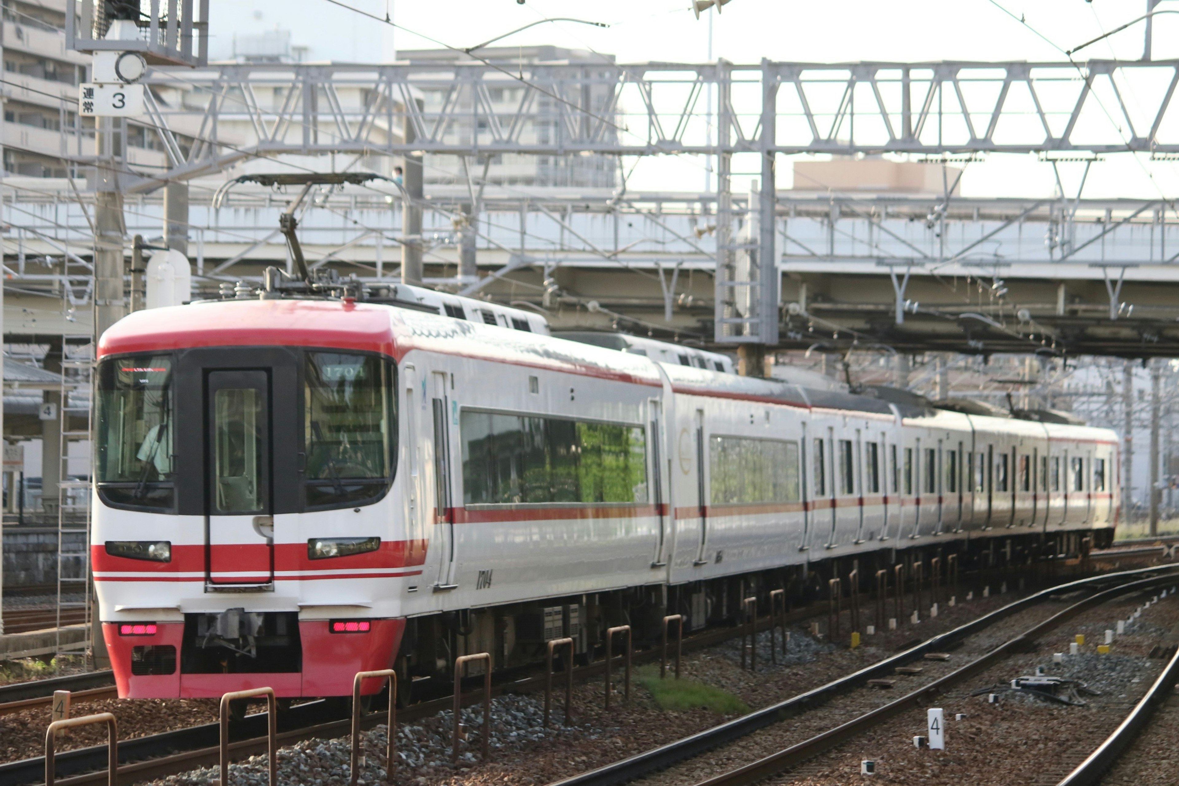 Red and white train running on tracks in an urban setting