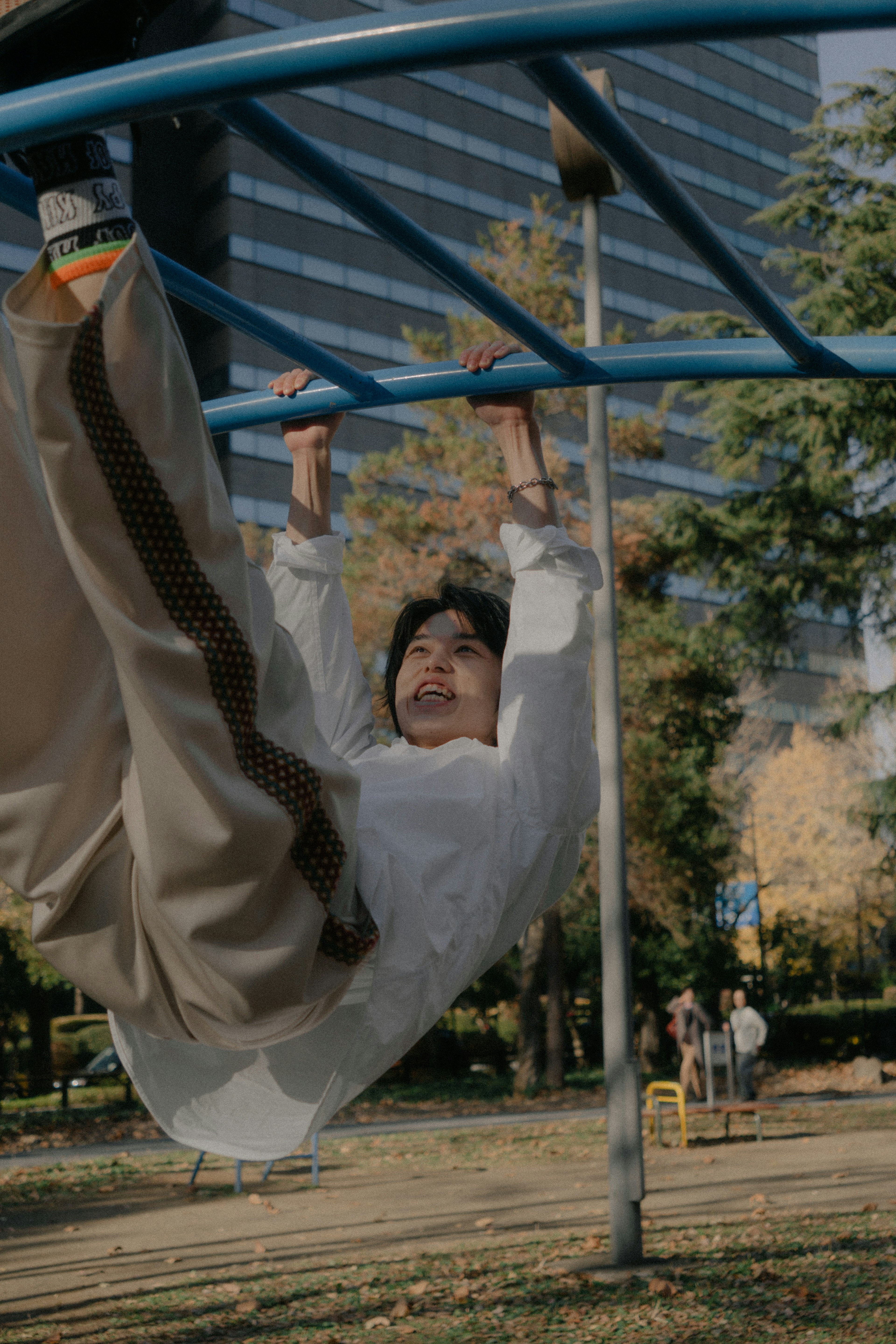 Giovane donna appesa a una struttura da gioco in un parco