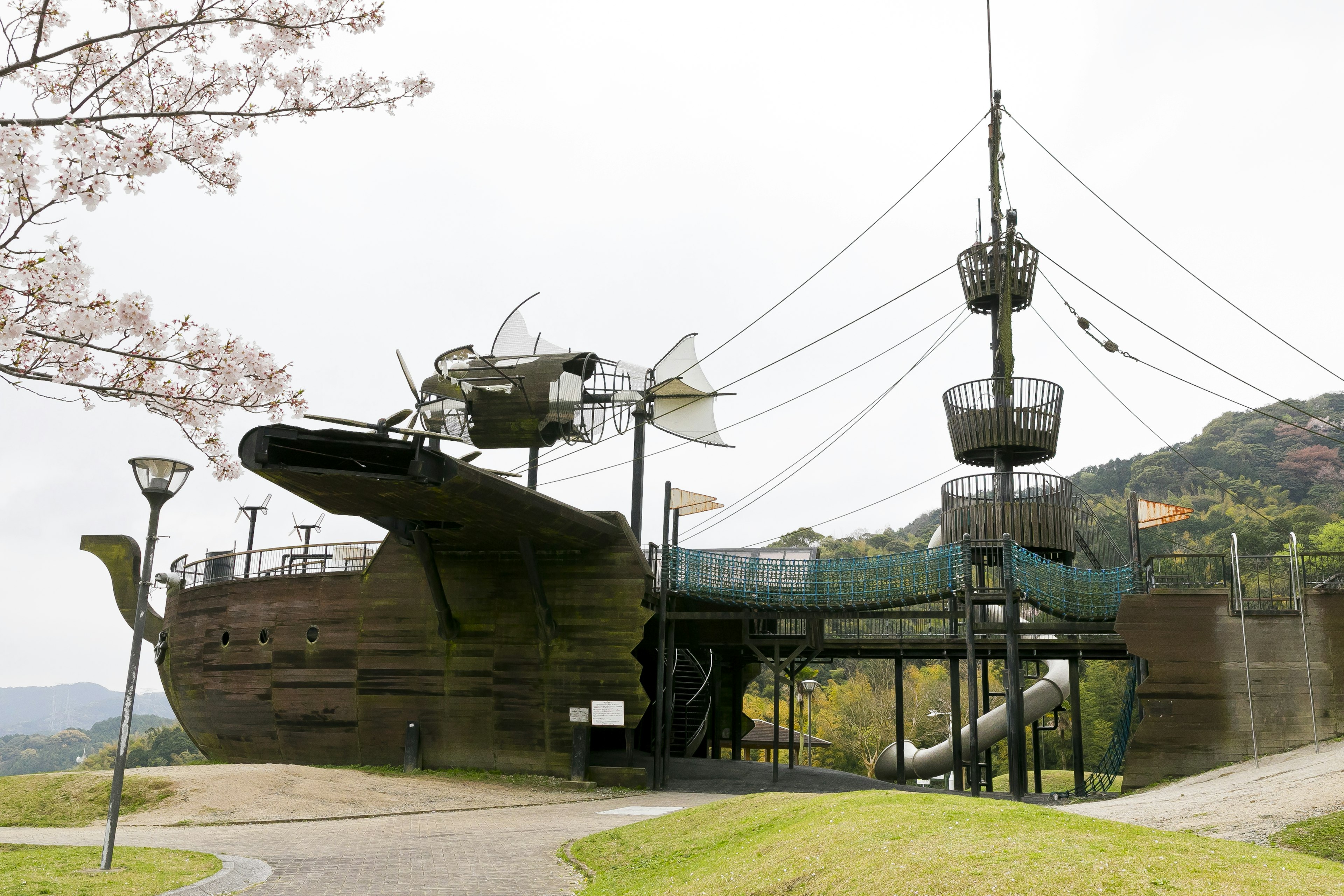 Une grande structure de jeu en forme de navire dans un parc avec des toboggans et des miradors