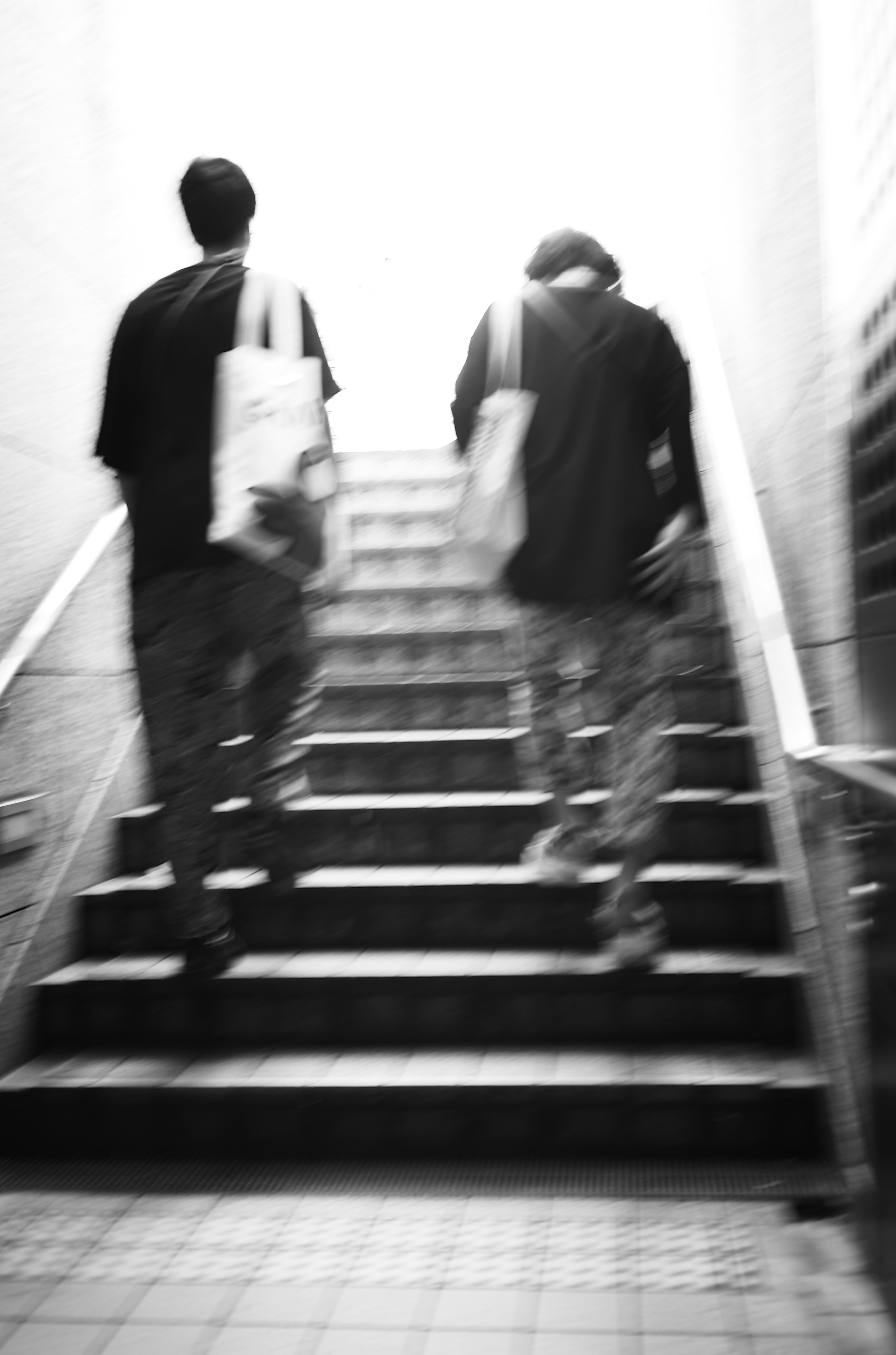 Two figures ascending stairs with bright light in the background