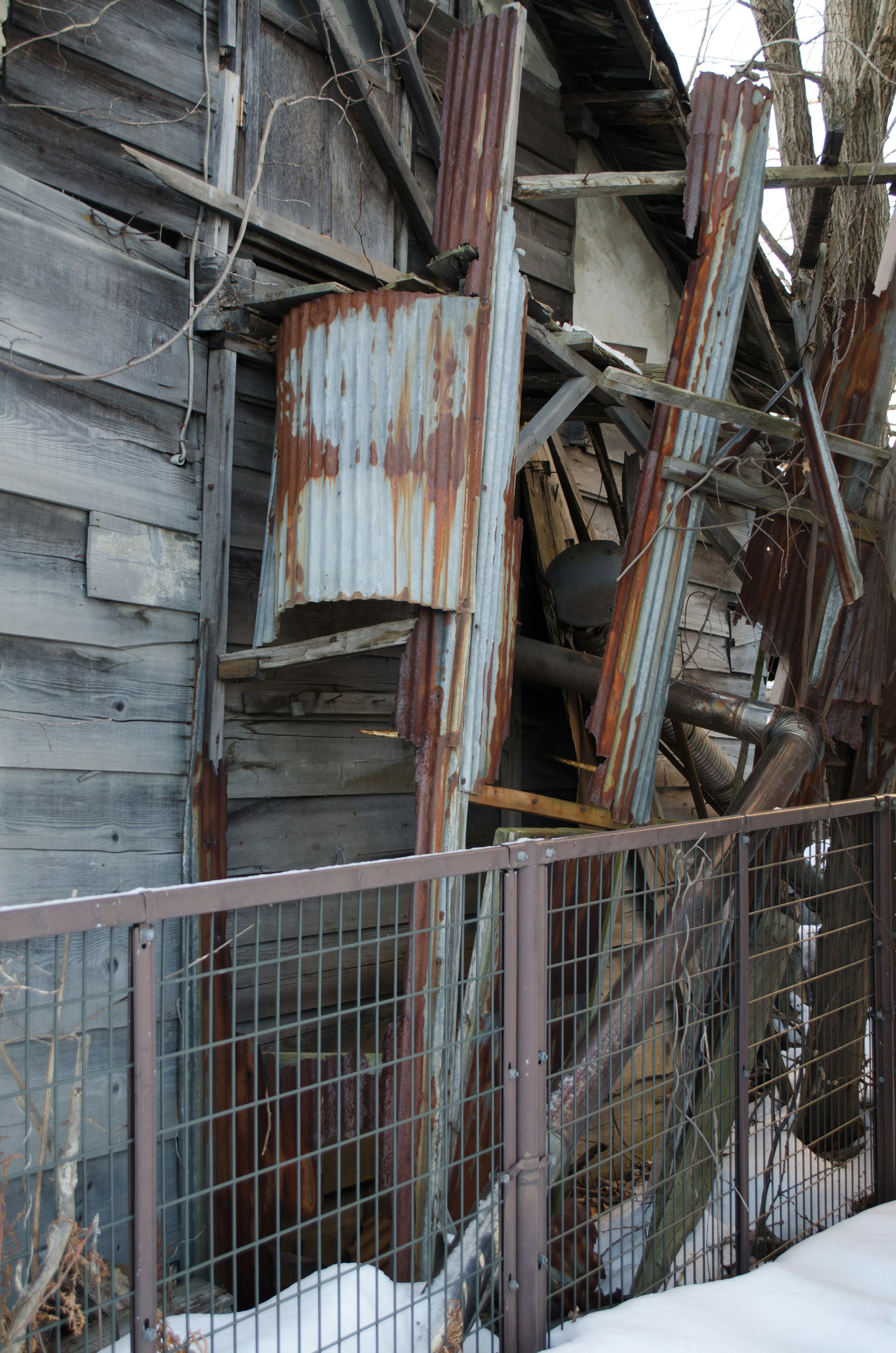 Part of an abandoned structure with weathered wood and rusty metal drums