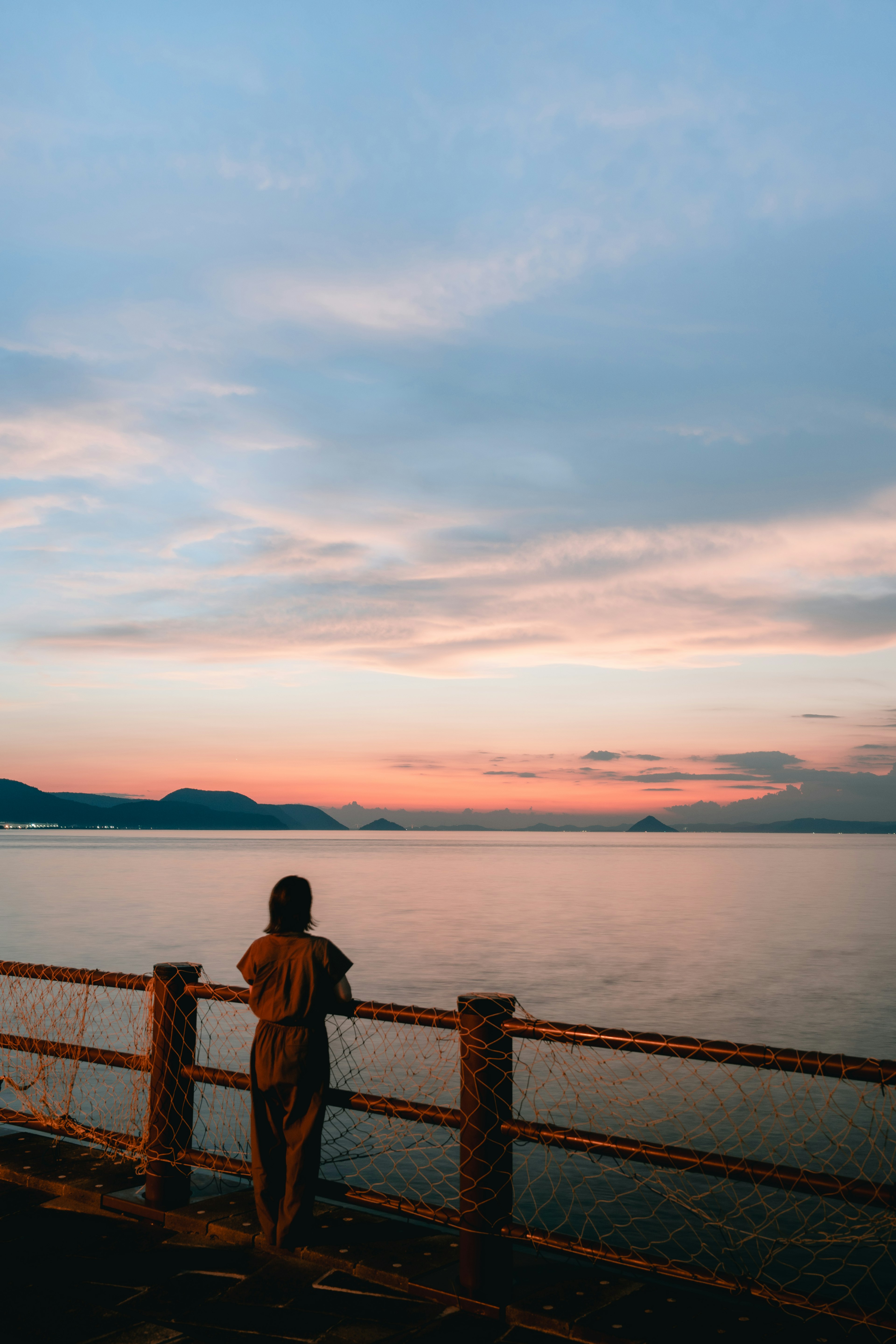 Silhouette d'une personne regardant le coucher de soleil au bord de la mer