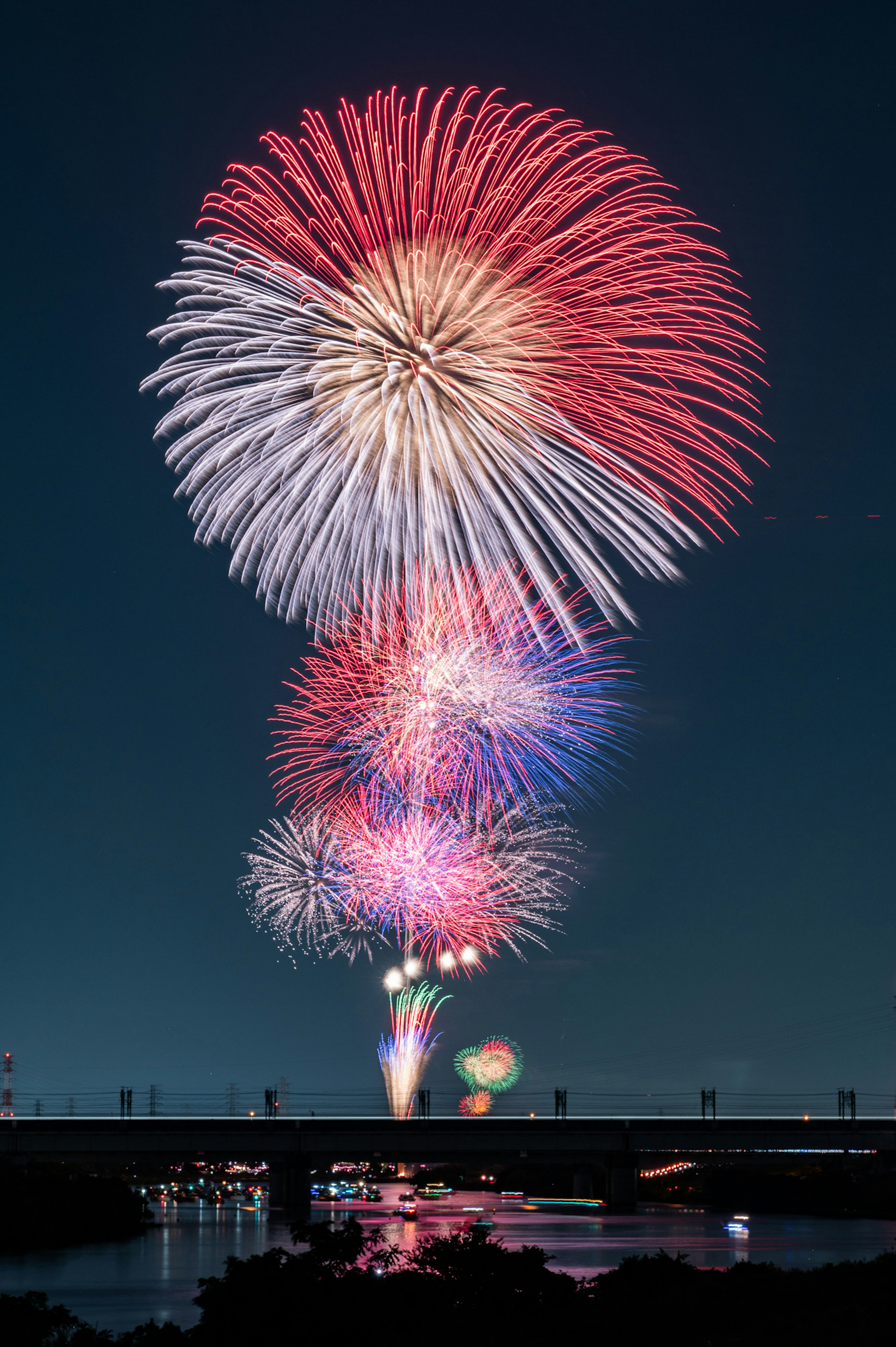 Fuochi d'artificio colorati esplodono nel cielo notturno riflettendosi sul fiume