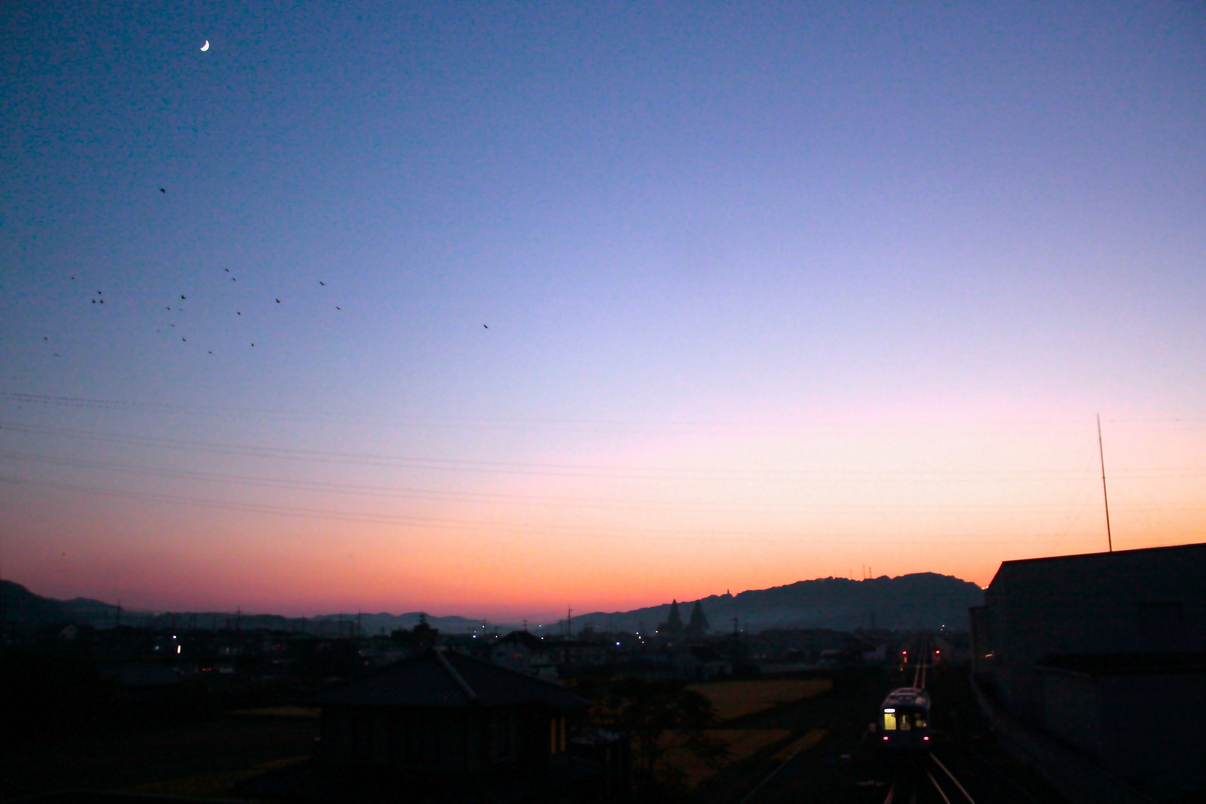 夕阳西下的景色，蓝色和橙色的渐变映照在远处的山丘上