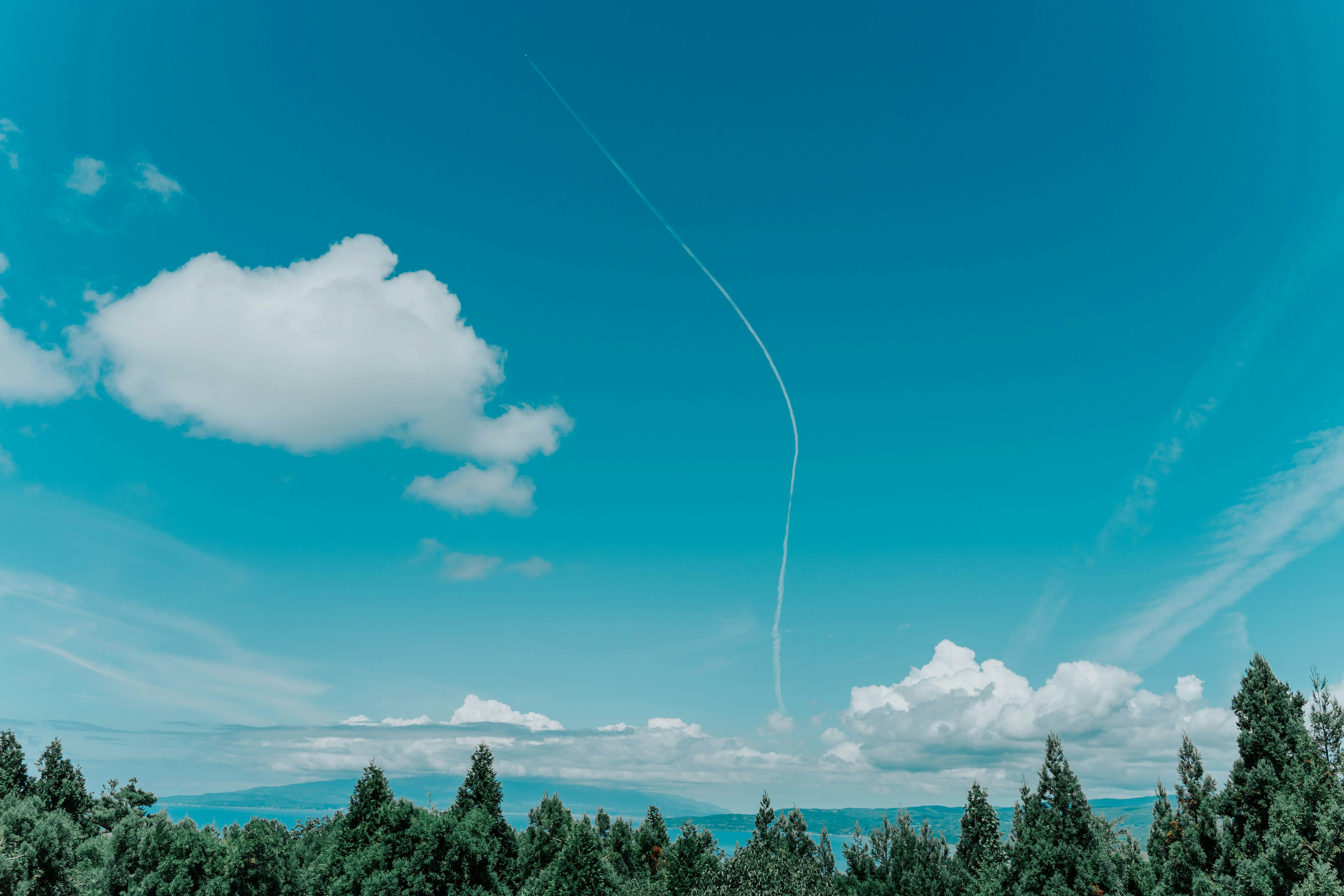 青空に白い雲と飛行機雲が見える風景