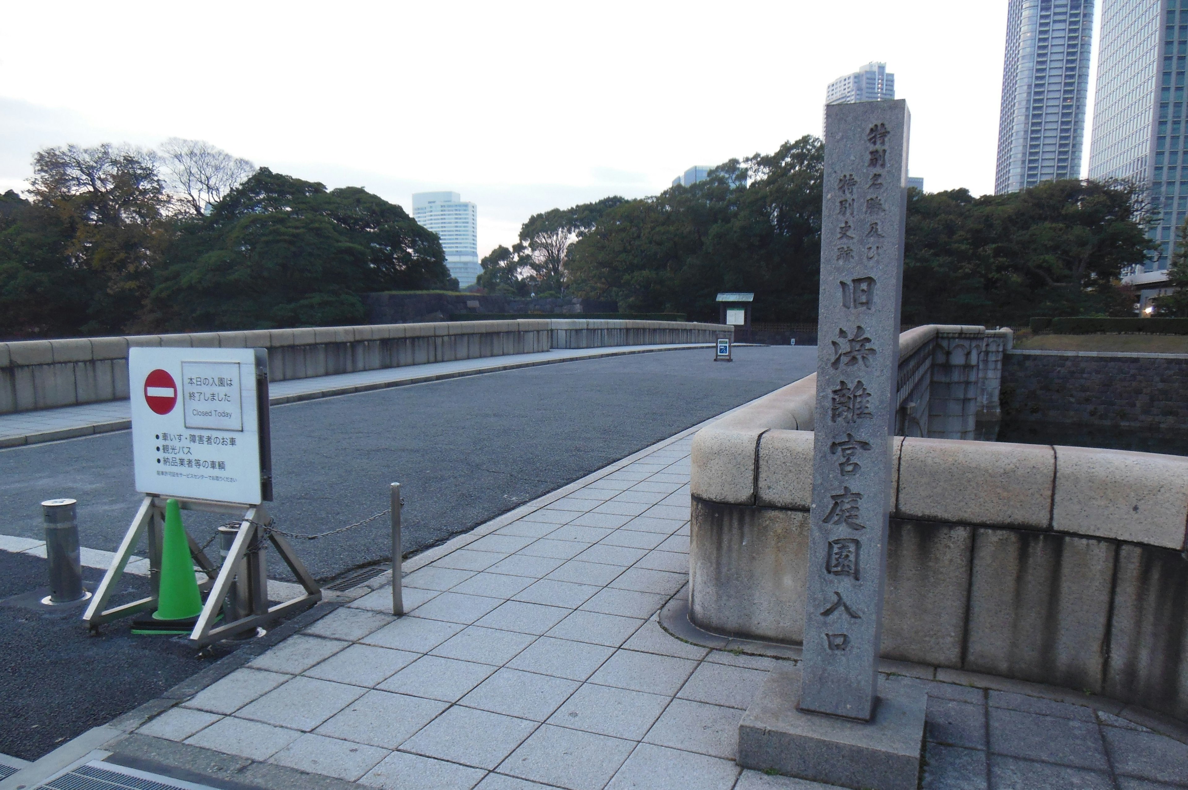 Steinschild, der den Eingang zu einem Park in Tokio mit der umliegenden Landschaft anzeigt