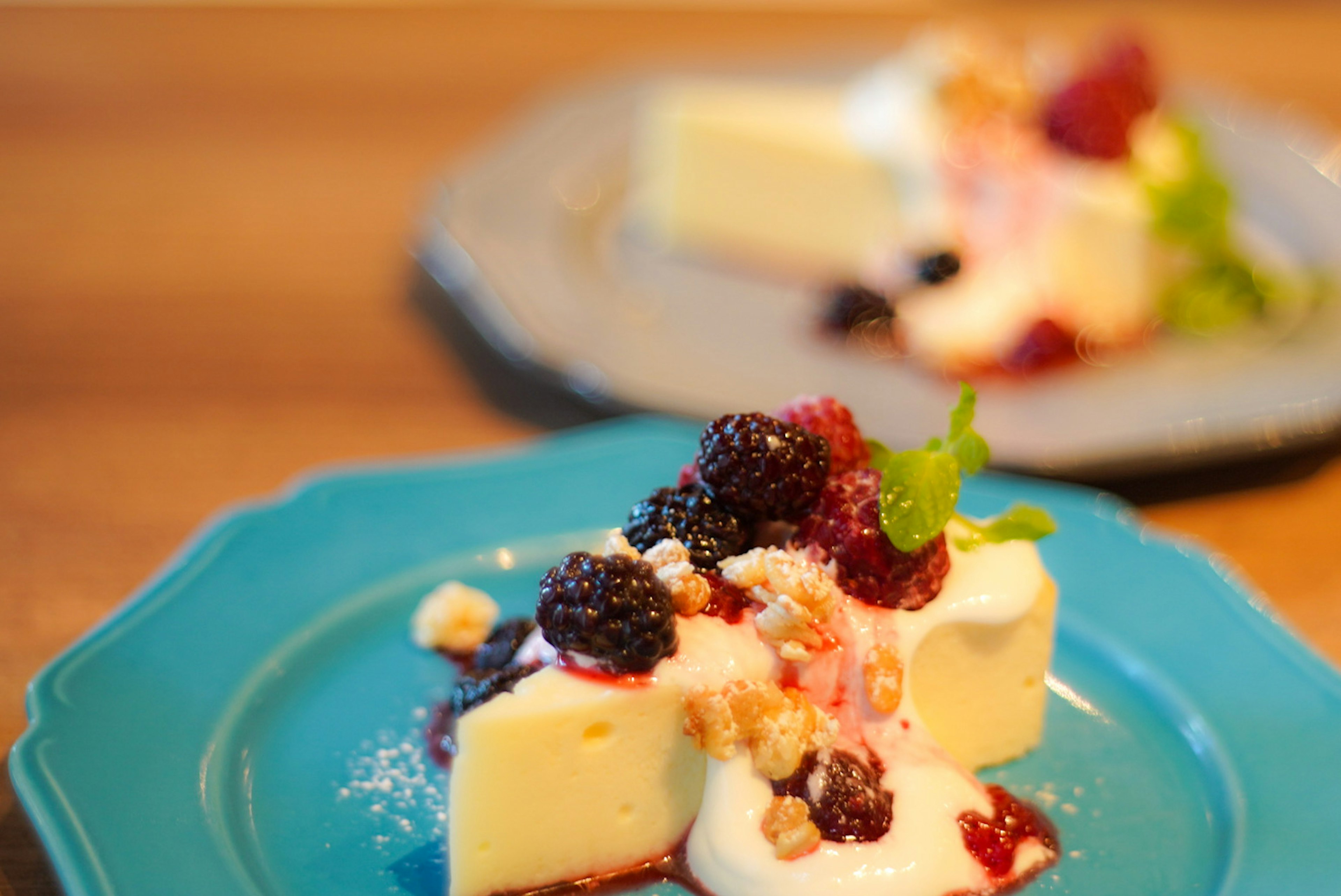 Slice of white dessert topped with berries and cream on a blue plate