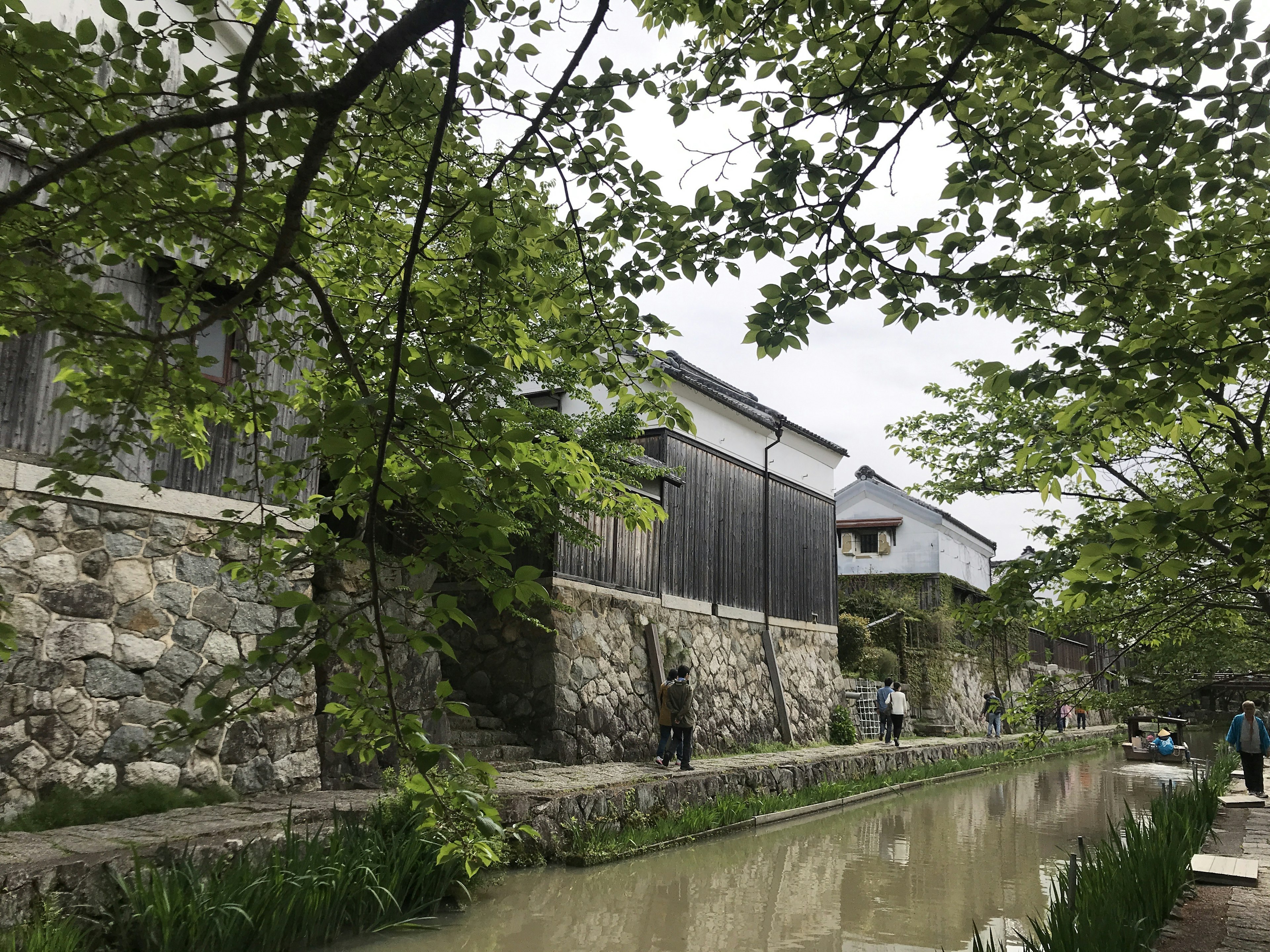 Vue pittoresque d'un vieux bâtiment le long d'un mur en pierre et d'un cours d'eau avec de la verdure