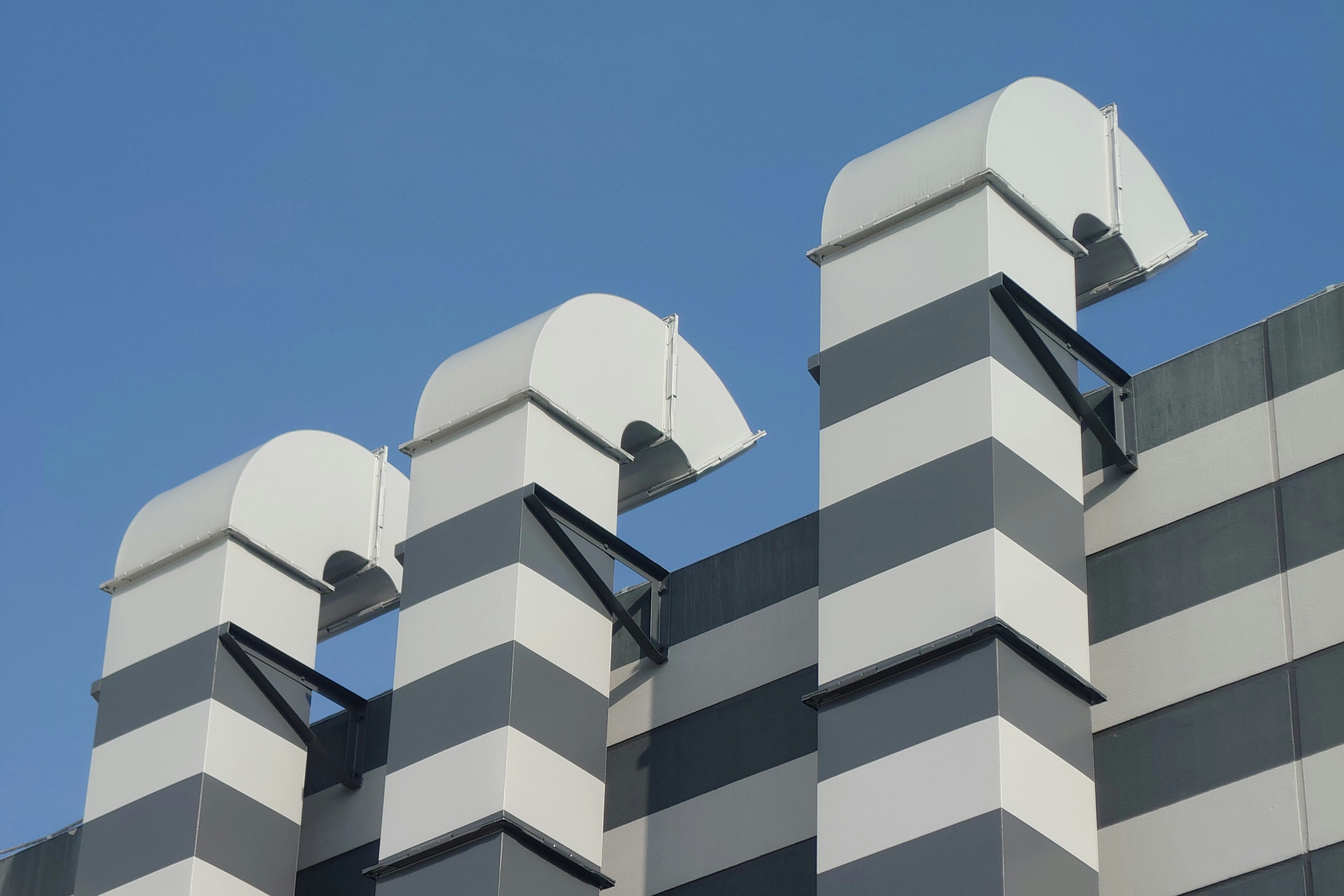 Façade de bâtiment rayée grise et blanche avec structures de ventilation courbées