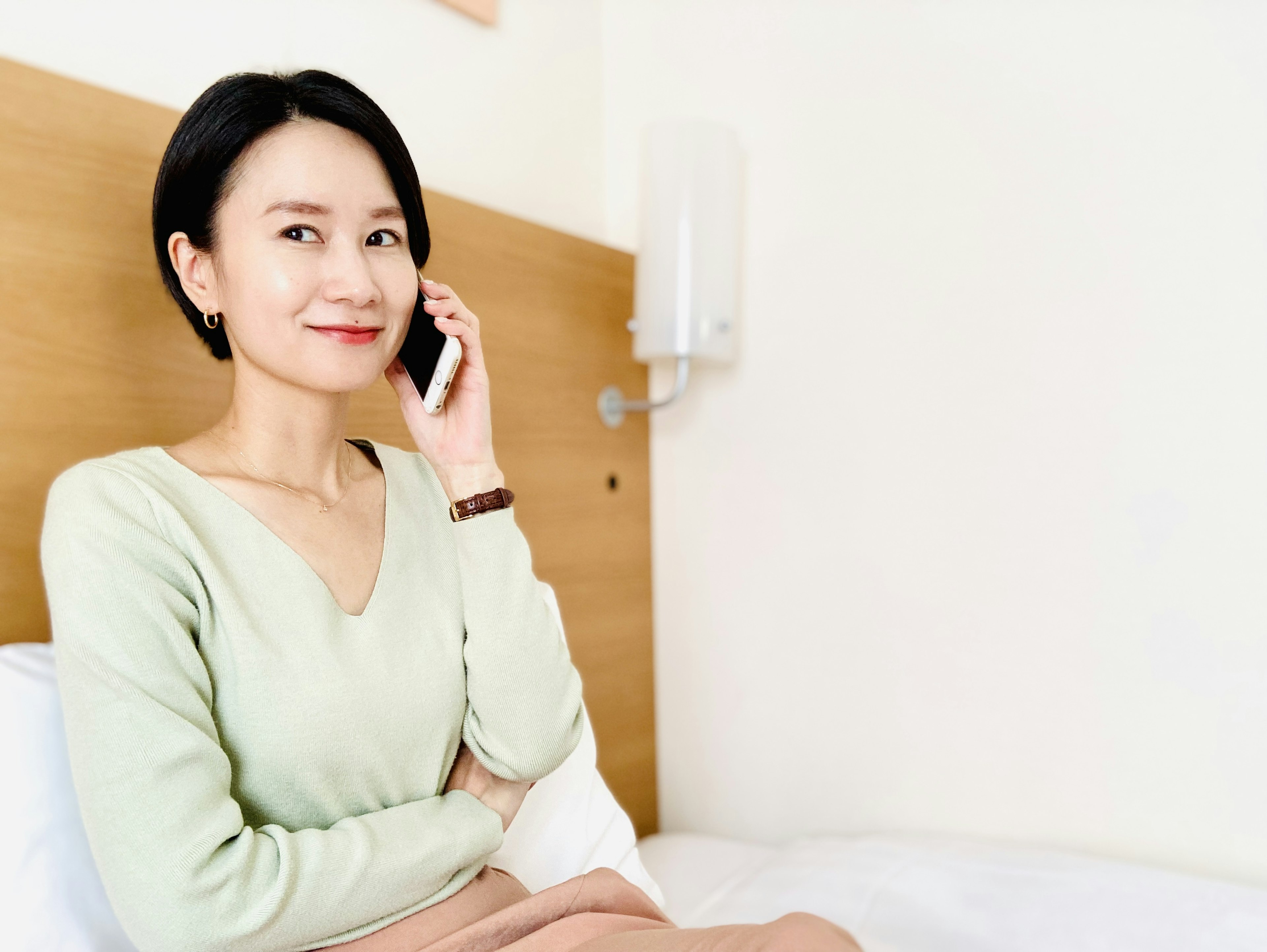 Woman smiling while talking on the phone sitting on a bed