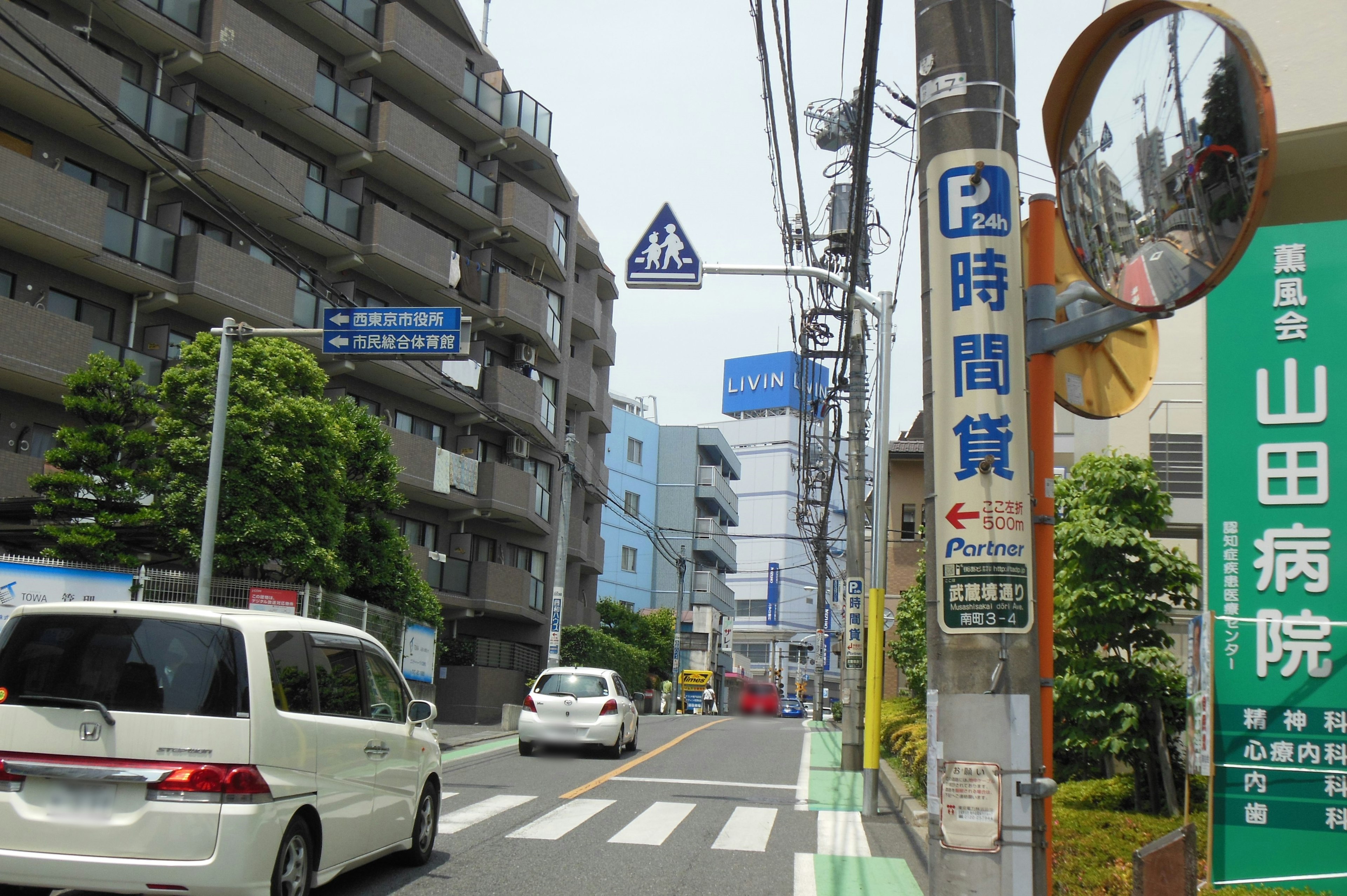 Residential street with white cars and signage visible