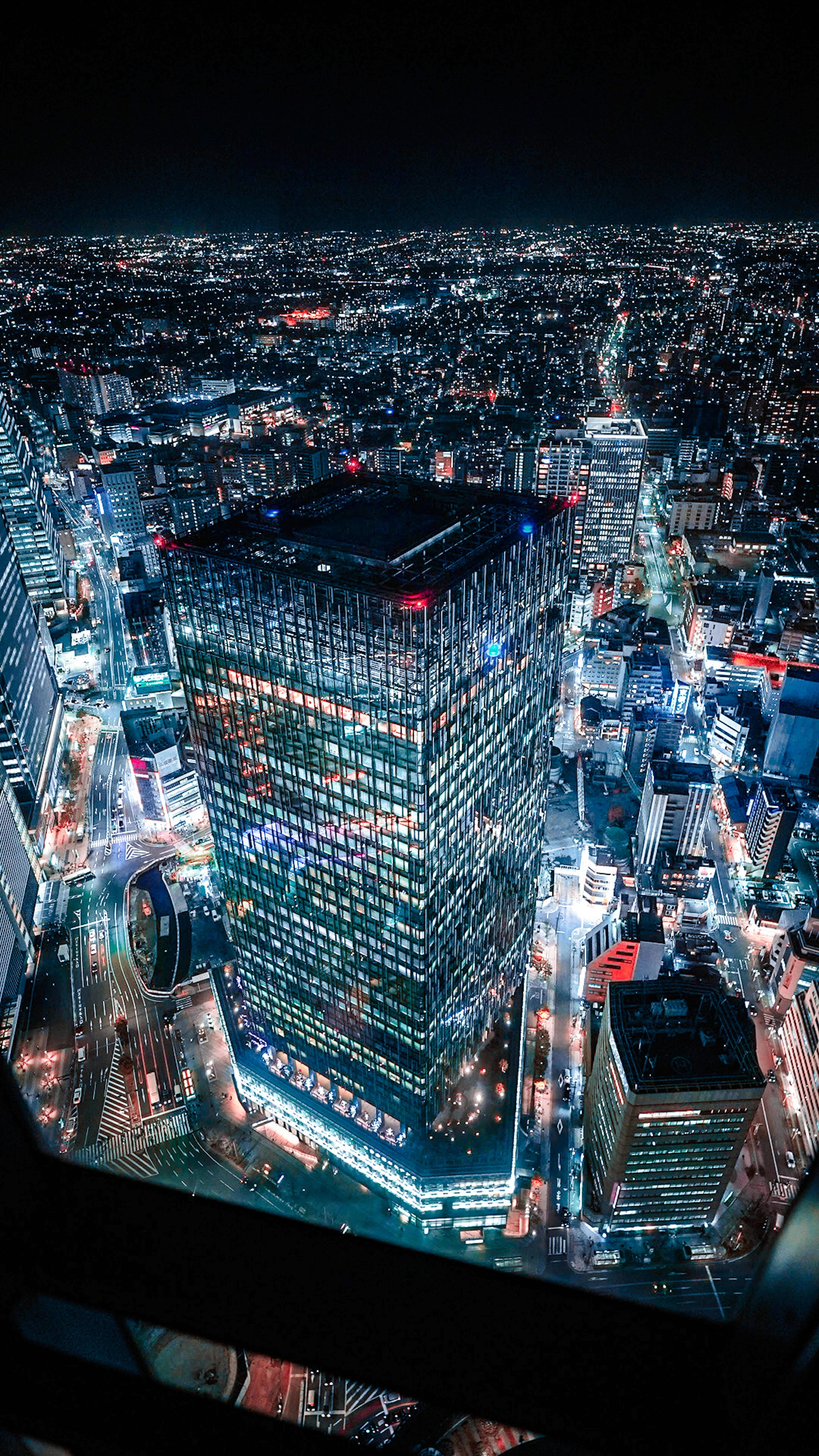 夜景の都市の上にそびえる高層ビルのドローンショット