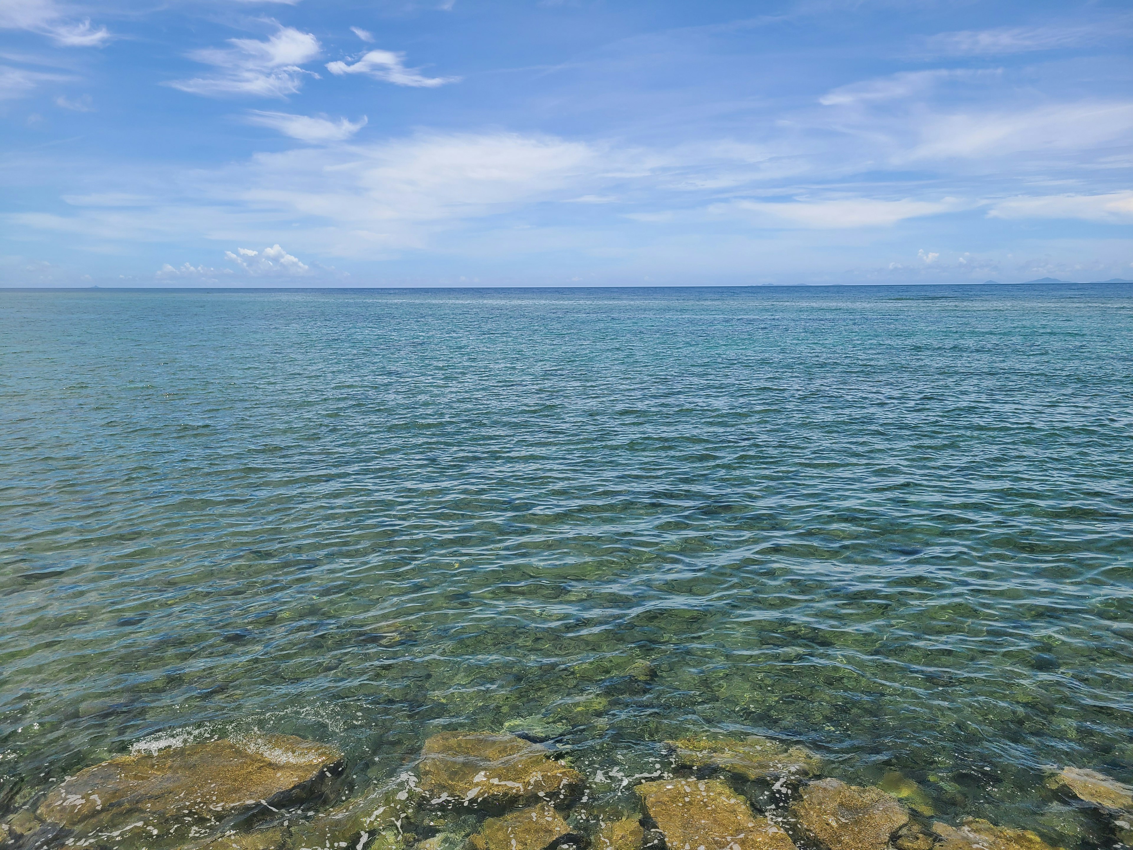 Pemandangan indah laut biru dan langit dengan pantai berbatu yang terlihat