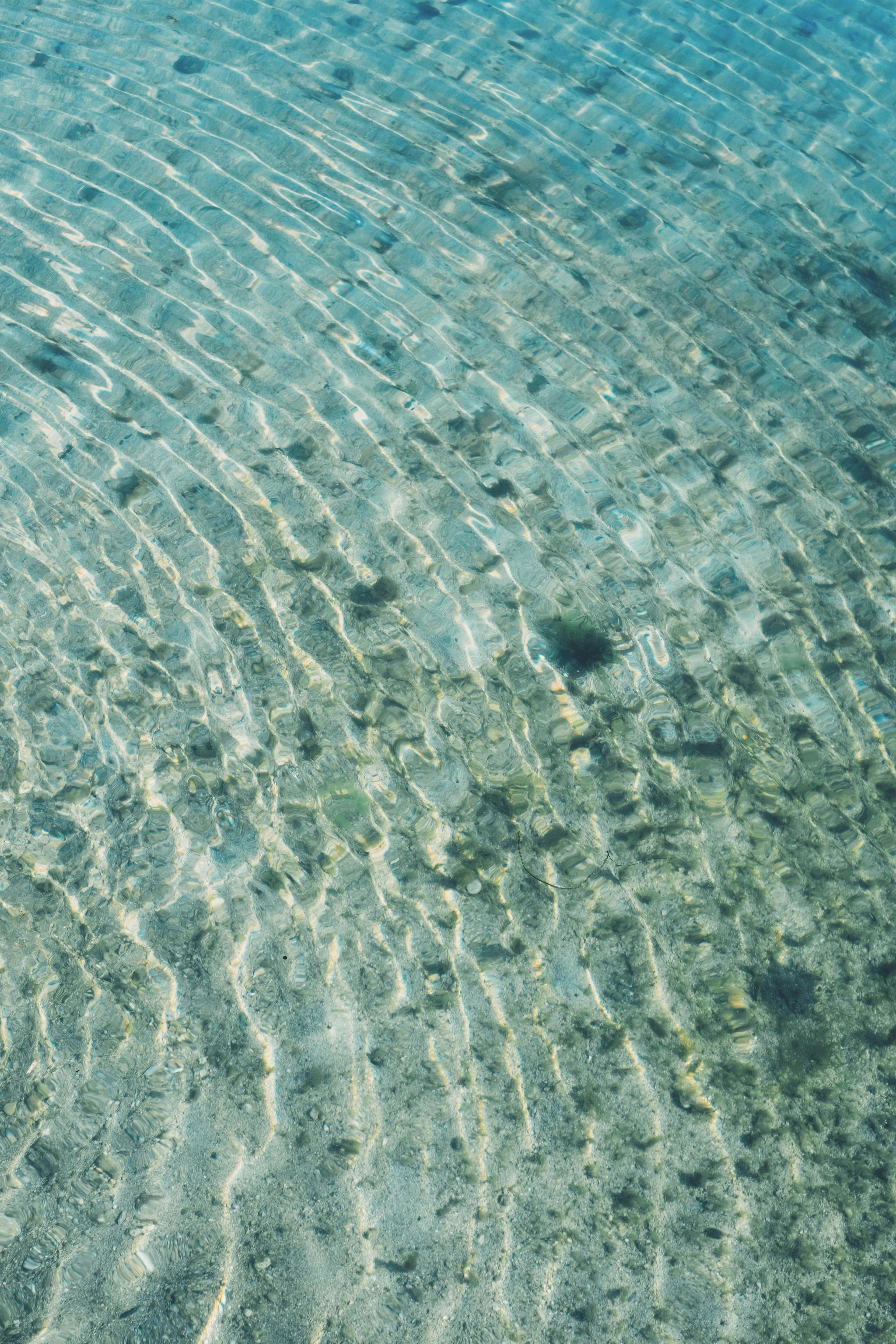 Klares Wasser mit Wellen über dem sandigen Meeresboden