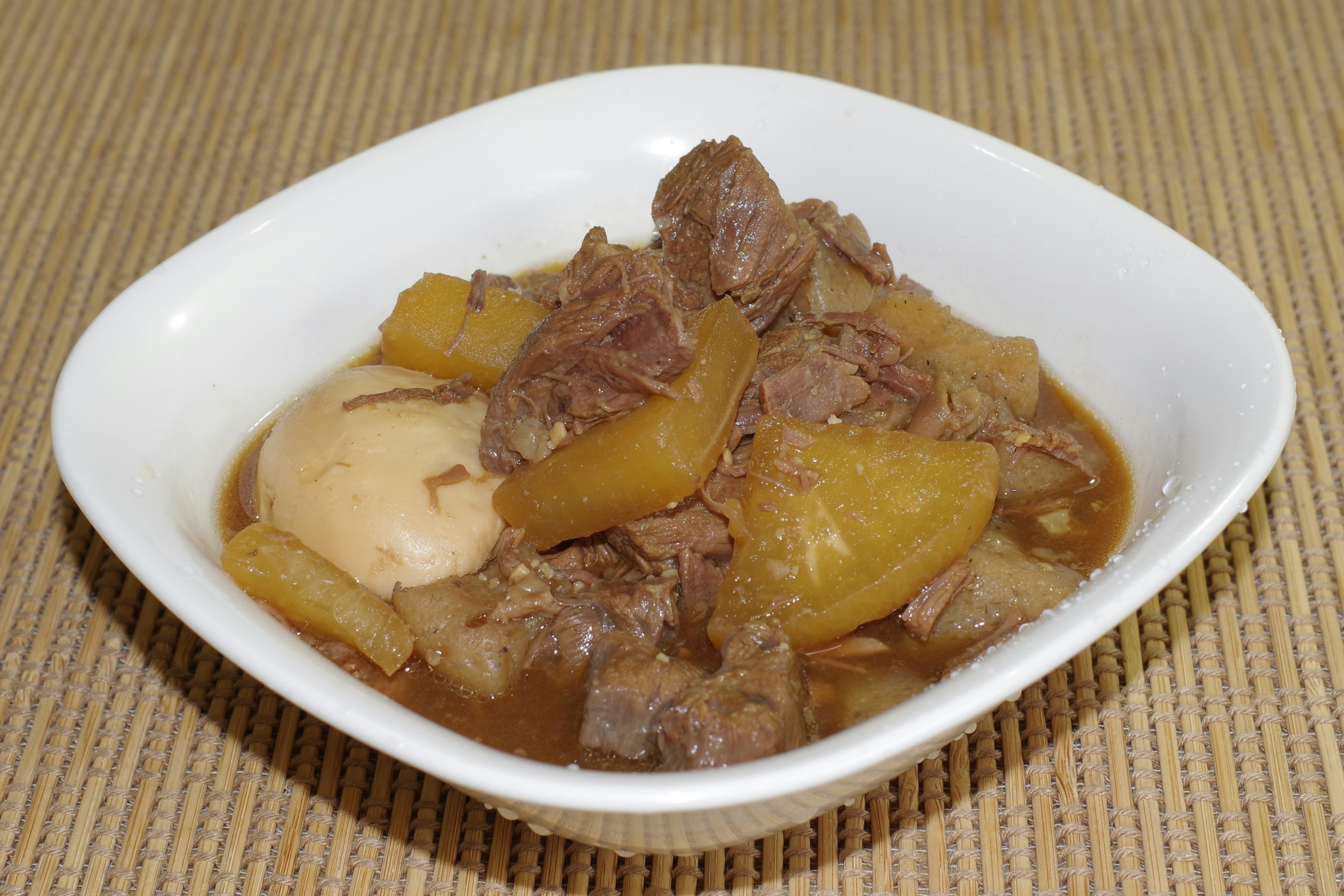 Braised meat and vegetables served in a white bowl