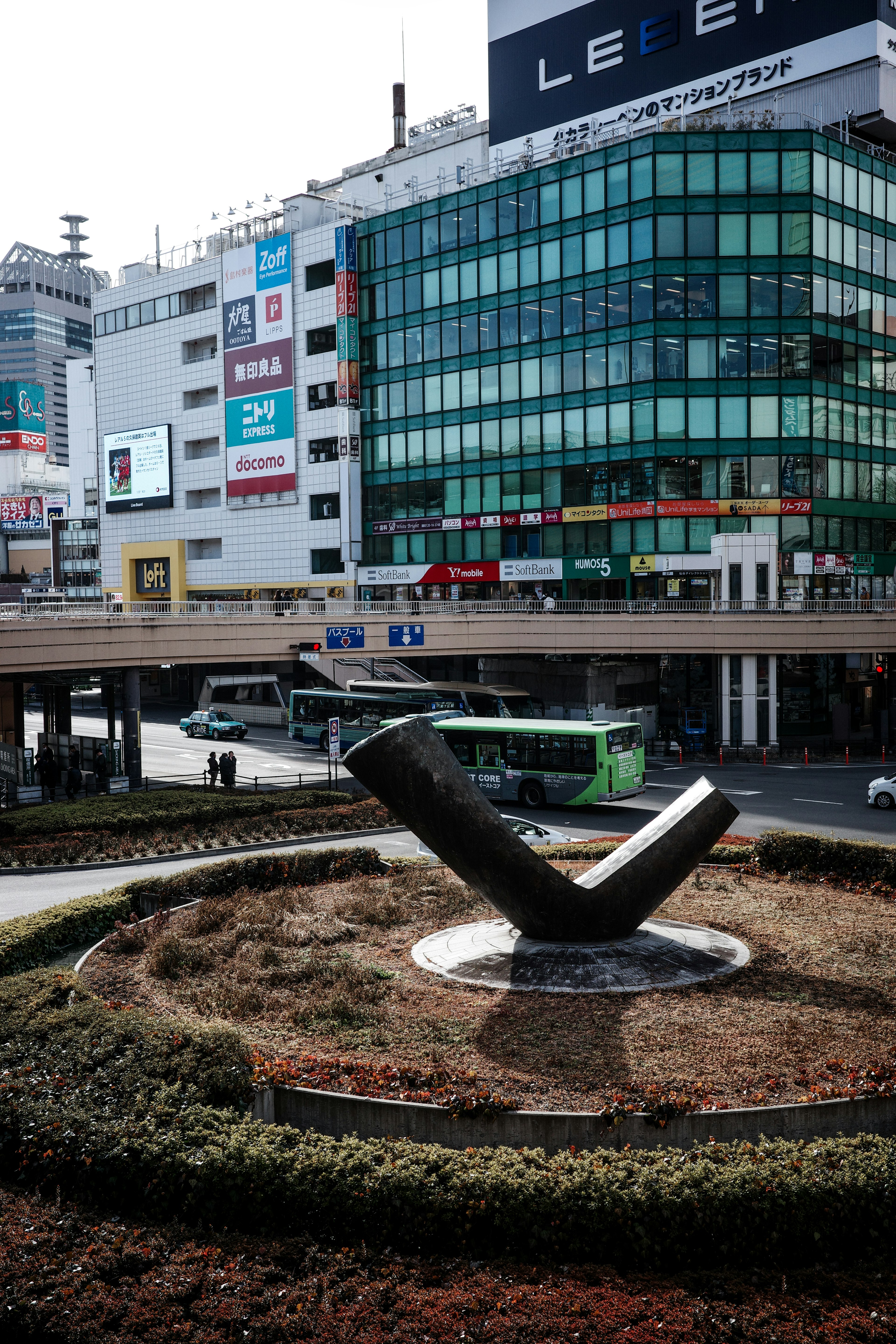 ビルの前にあるモダンな彫刻と周囲の緑地