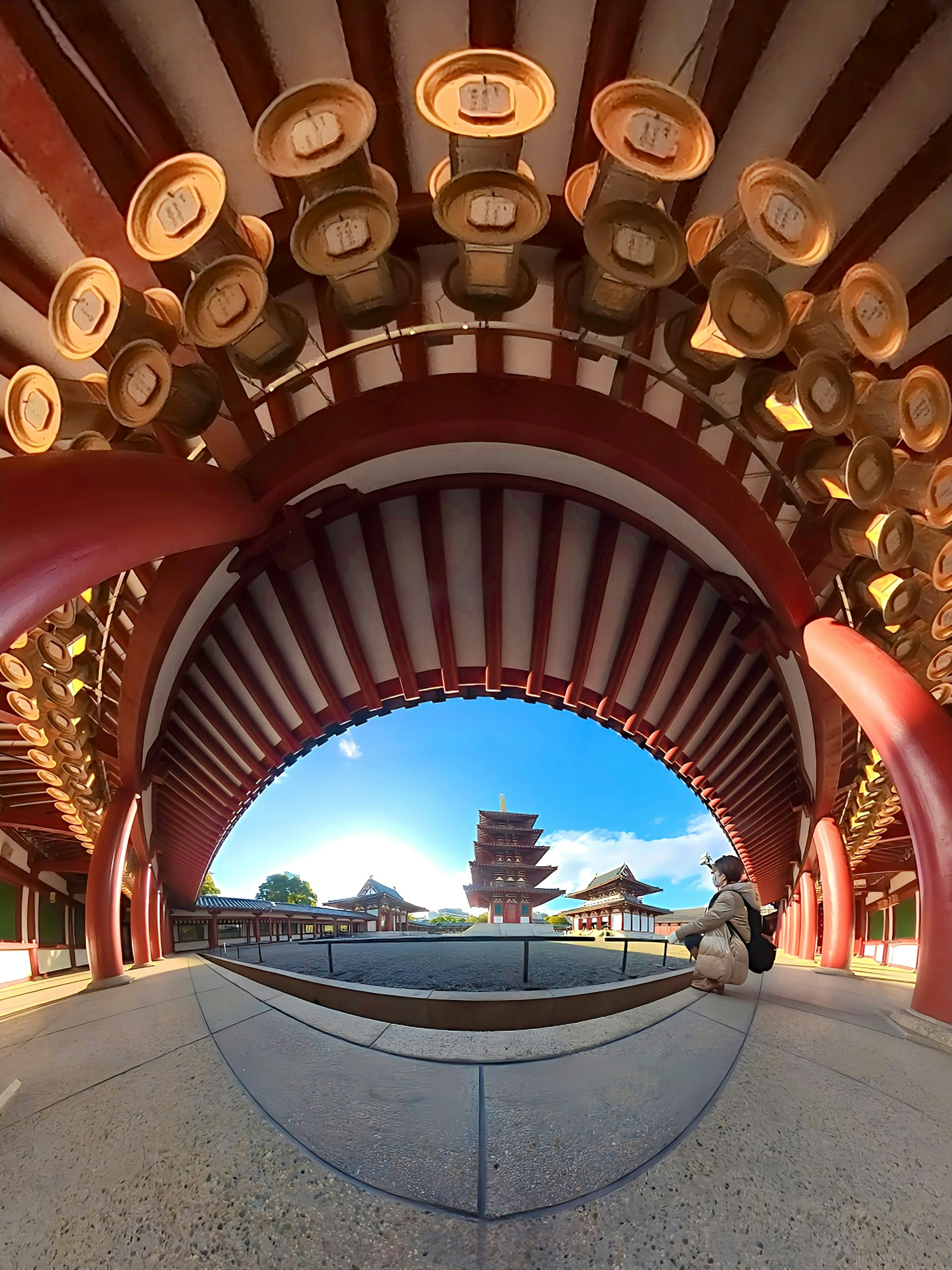 Architectural view of a temple featuring red columns and arches under a blue sky